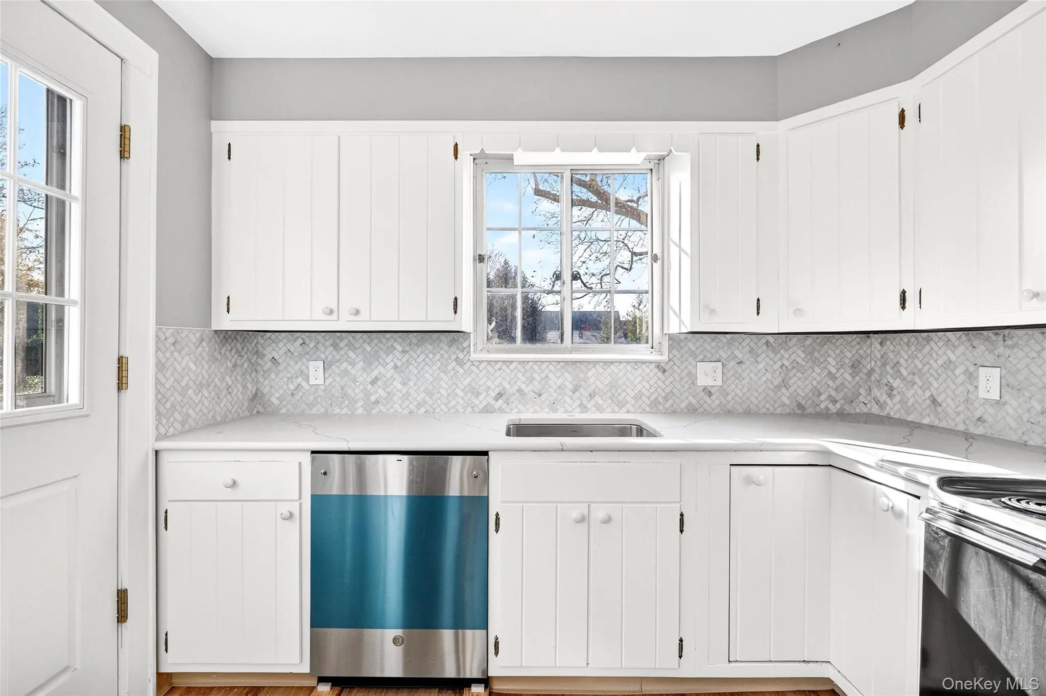 Kitchen featuring stainless steel appliances, white cabinetry, and light stone counters Kitchen featuring stainless steel appliances, white cabinetry, and light stone counters