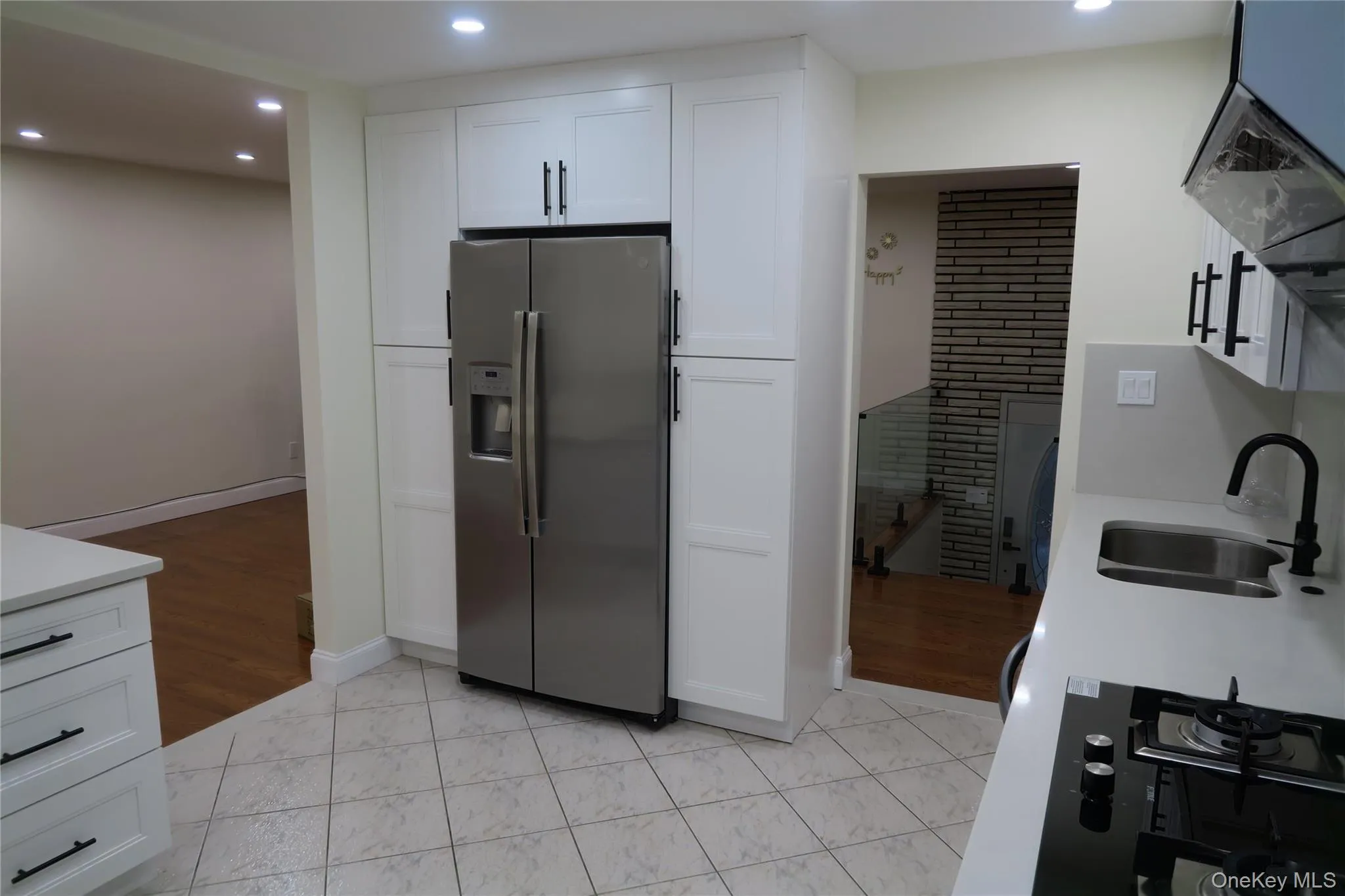 Kitchen with stainless steel fridge, white cabinetry, gas cooktop, recessed lighting, and light wood-type flooring Kitchen with stainless steel fridge, white cabinetry, gas cooktop, recessed lighting, and light wood-type flooring