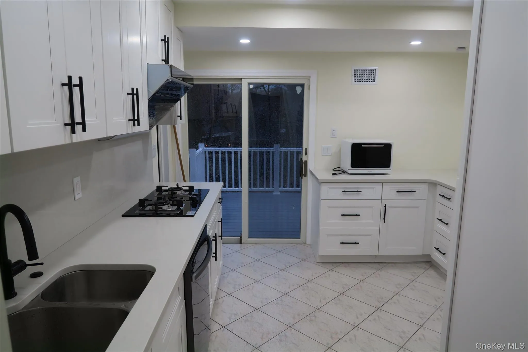 Kitchen with white cabinets, range hood, black appliances, recessed lighting, and light stone counters Kitchen with white cabinets, range hood, black appliances, recessed lighting, and light stone counters