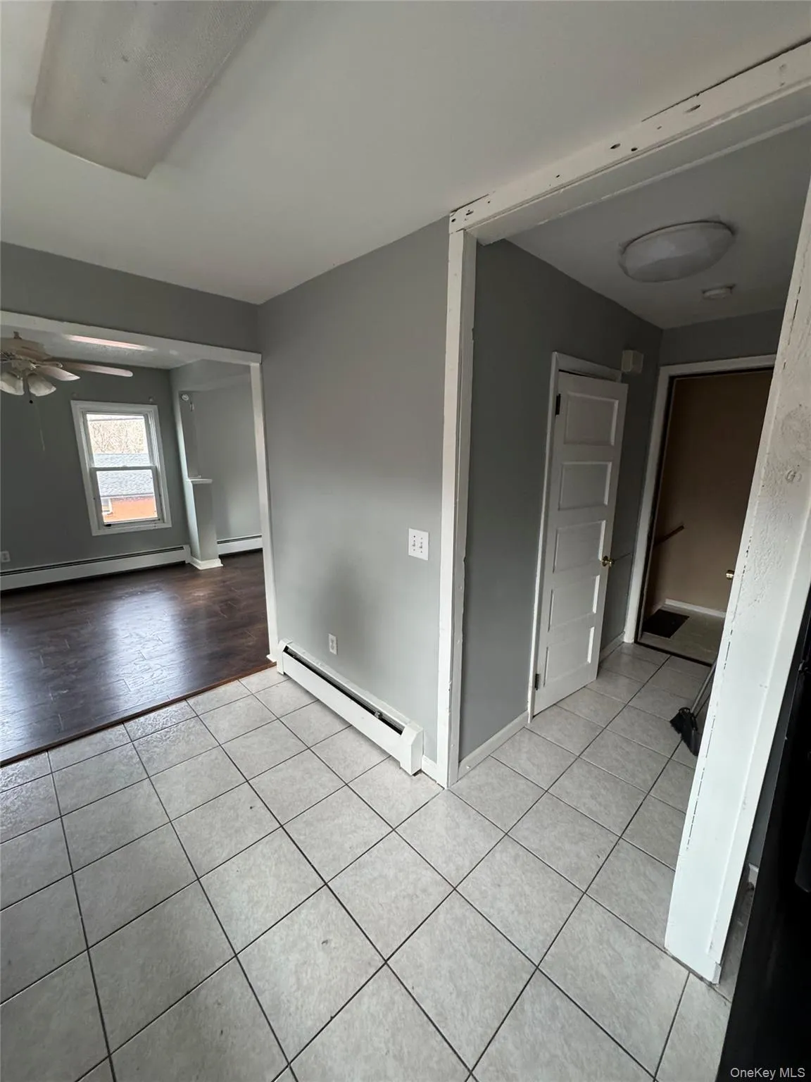 Unfurnished room with baseboard heating, a ceiling fan, and light tile patterned flooring Unfurnished room with baseboard heating, a ceiling fan, and light tile patterned flooring