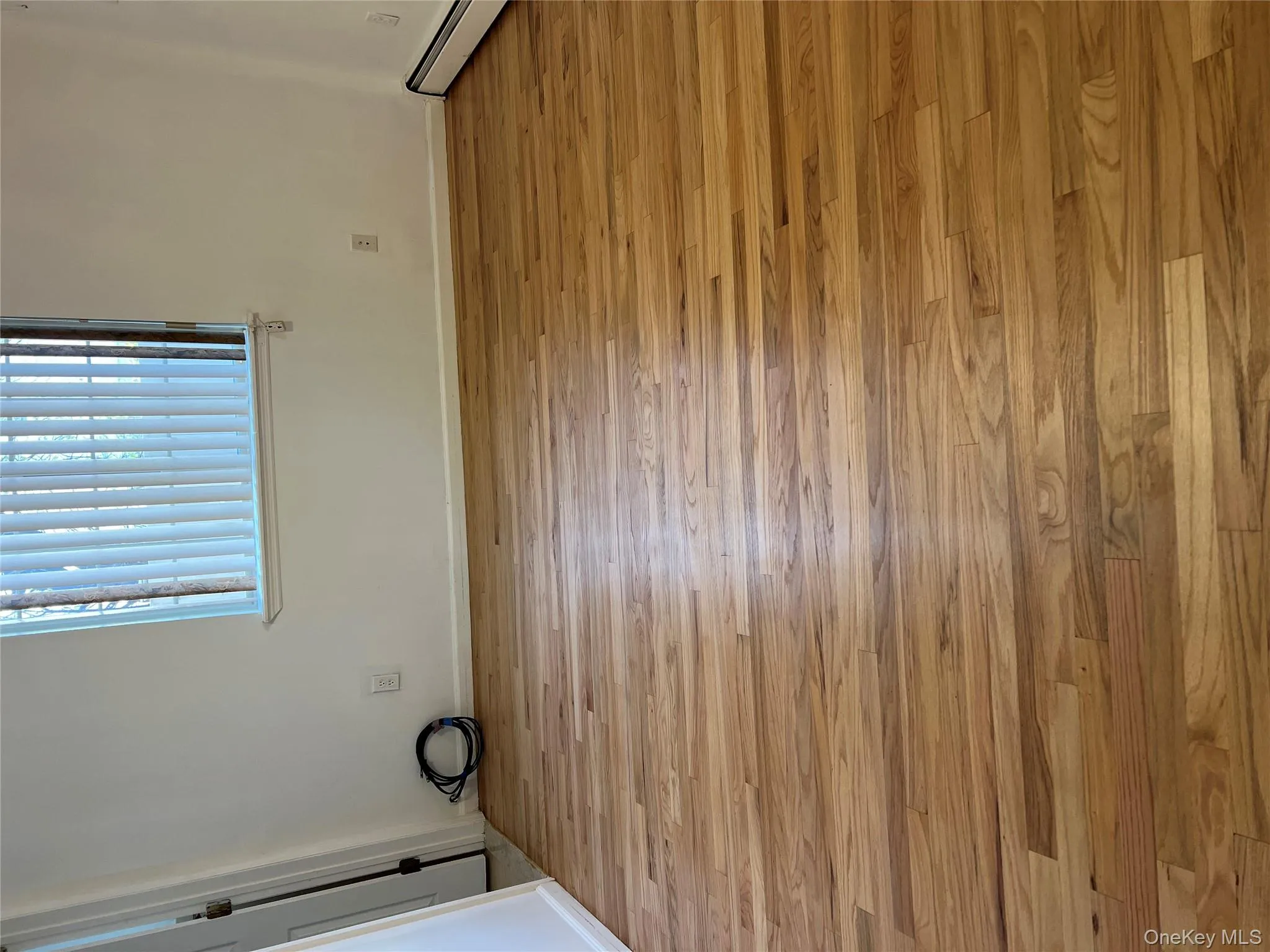 Empty room with a baseboard heating unit and light wood-style flooring Empty room with a baseboard heating unit and light wood-style flooring