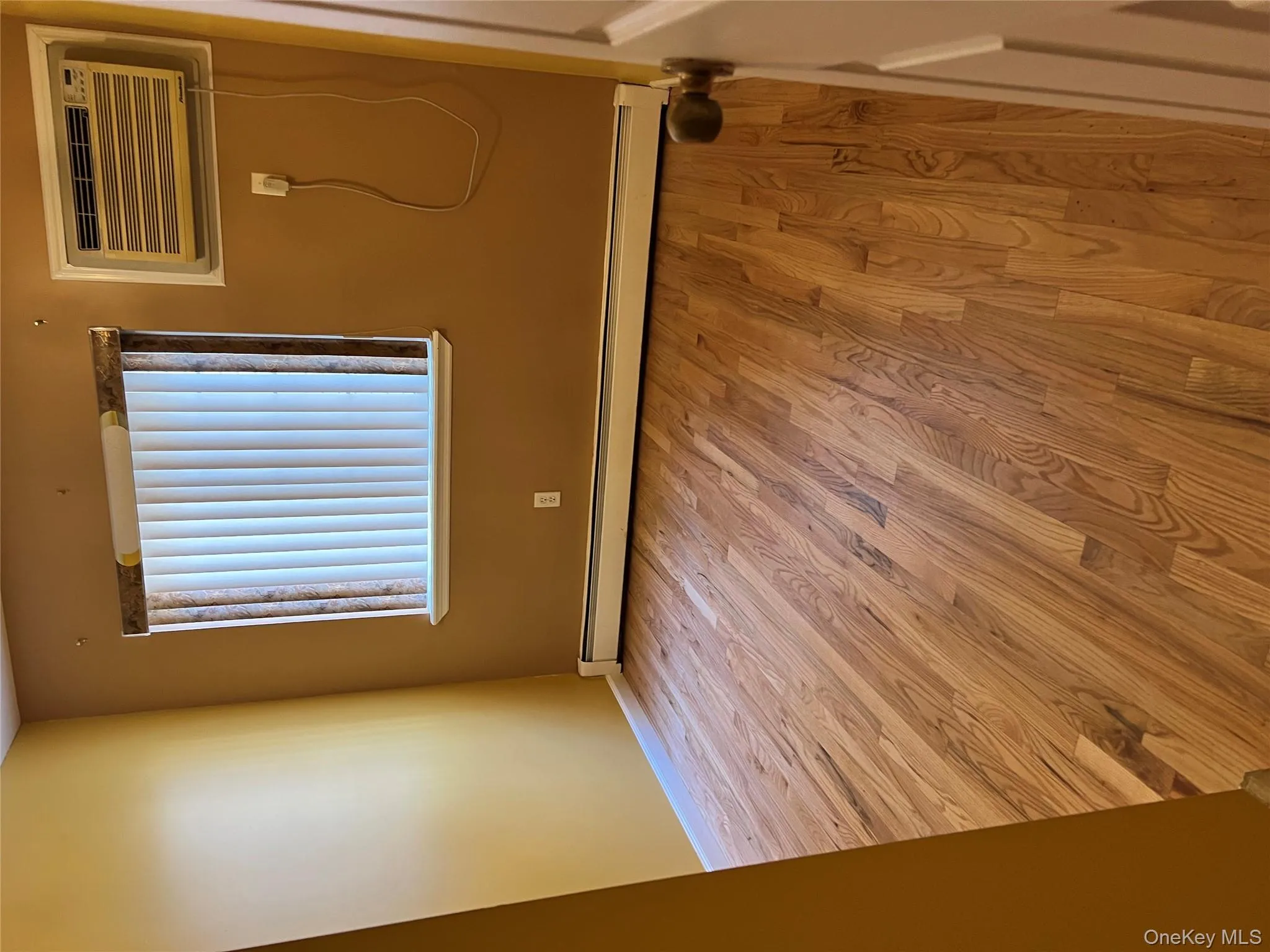 Spare room with light wood-style floors, a baseboard heating unit, and a wall unit AC Spare room with light wood-style floors, a baseboard heating unit, and a wall unit AC