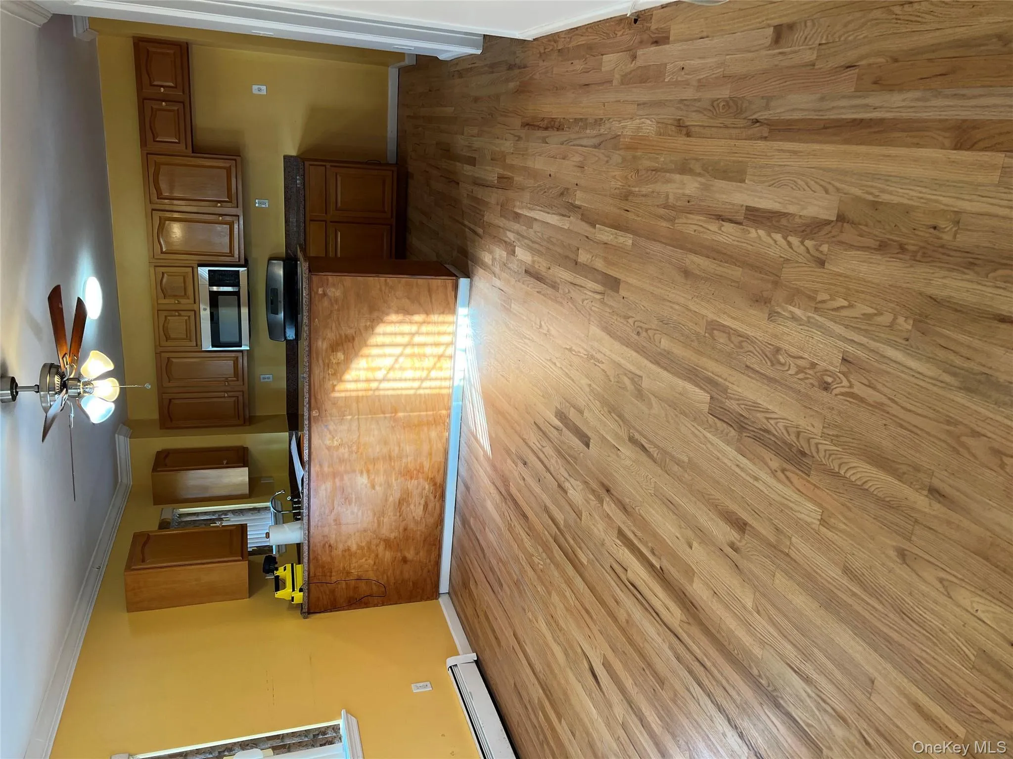 Kitchen with brown cabinets, dark countertops, a baseboard radiator, light wood-style floors, and ornamental molding Kitchen with brown cabinets, dark countertops, a baseboard radiator, light wood-style floors, and ornamental molding