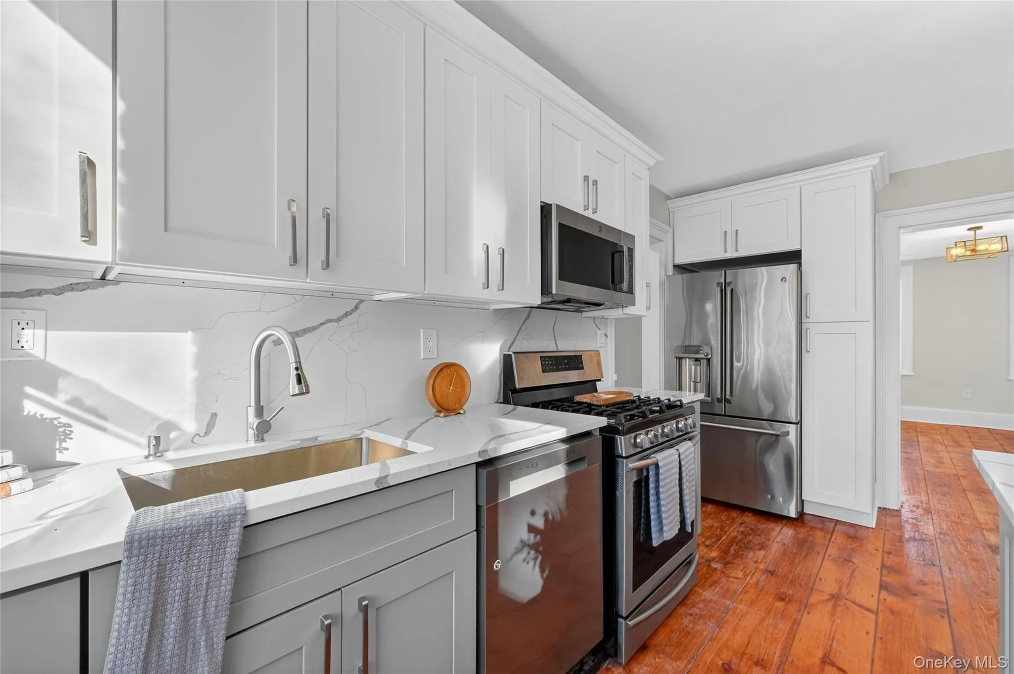 Kitchen featuring stainless steel appliances, backsplash, white cabinetry, and light stone countertops Kitchen featuring stainless steel appliances, backsplash, white cabinetry, and light stone countertops