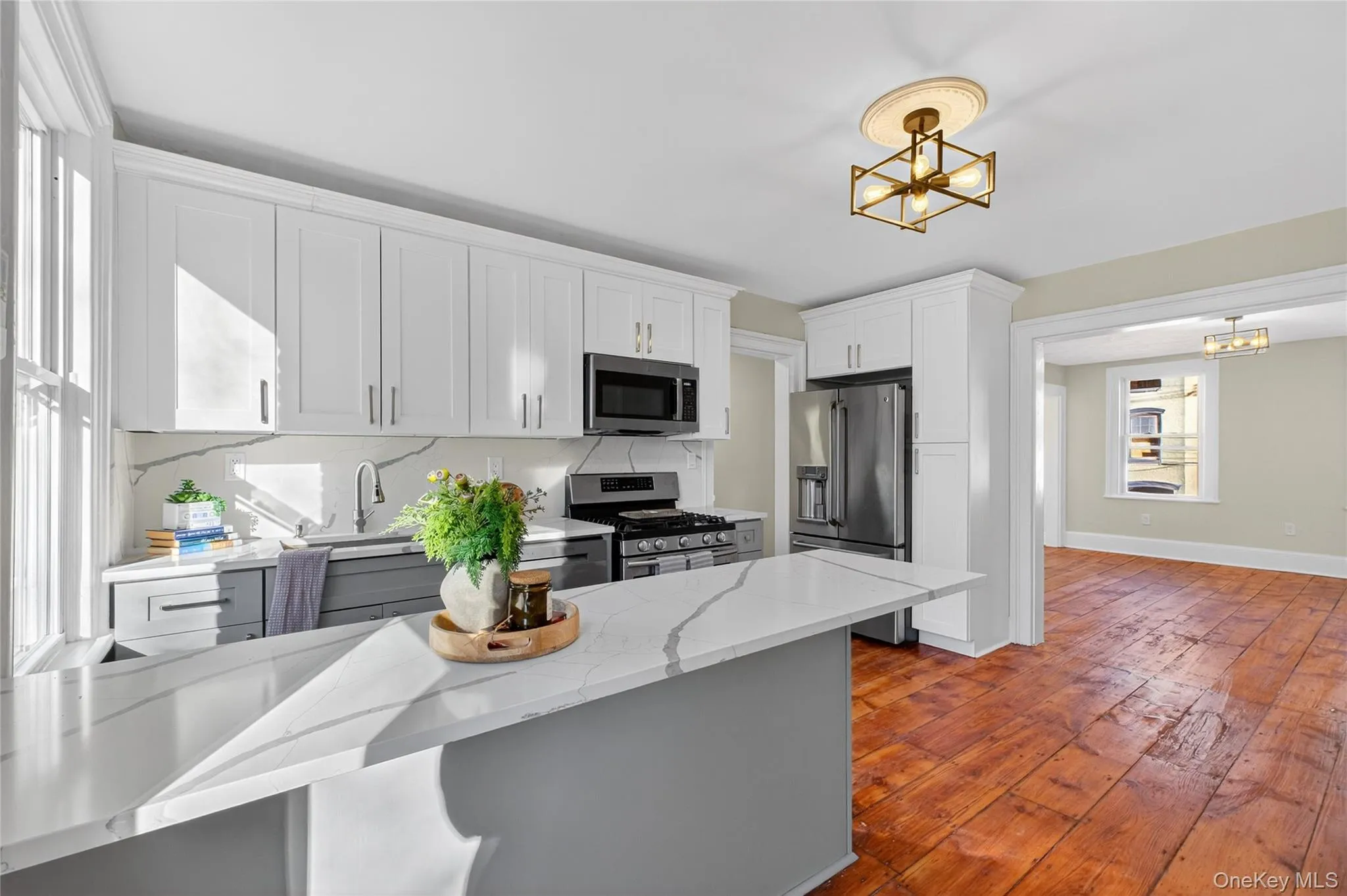 Kitchen with stainless steel appliances, white cabinets, light stone countertops, and a chandelier Kitchen with stainless steel appliances, white cabinets, light stone countertops, and a chandelier