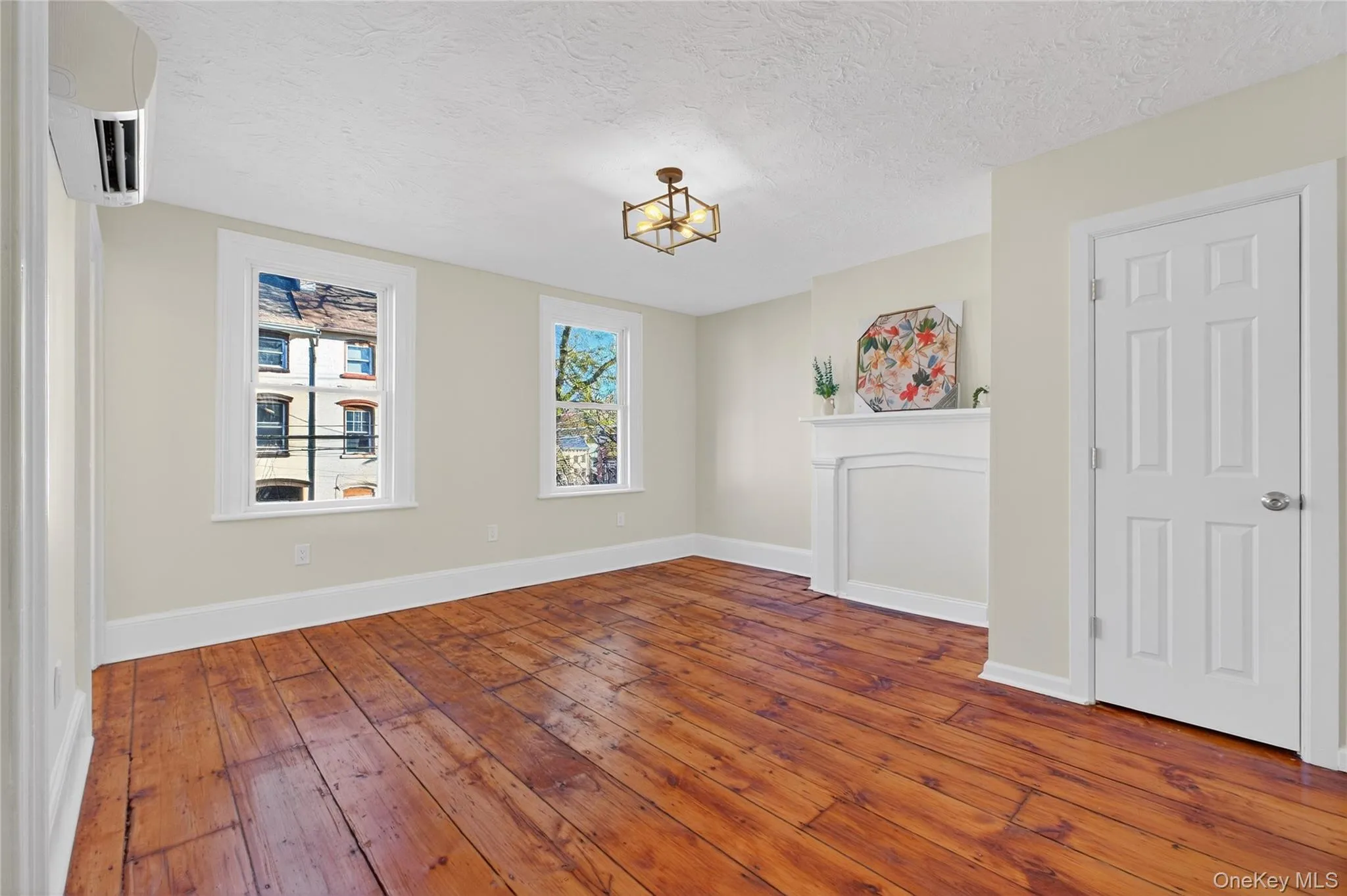 Spare room featuring a textured ceiling, dark wood finished floors, a wall unit AC, and a chandelier Spare room featuring a textured ceiling, dark wood finished floors, a wall unit AC, and a chandelier