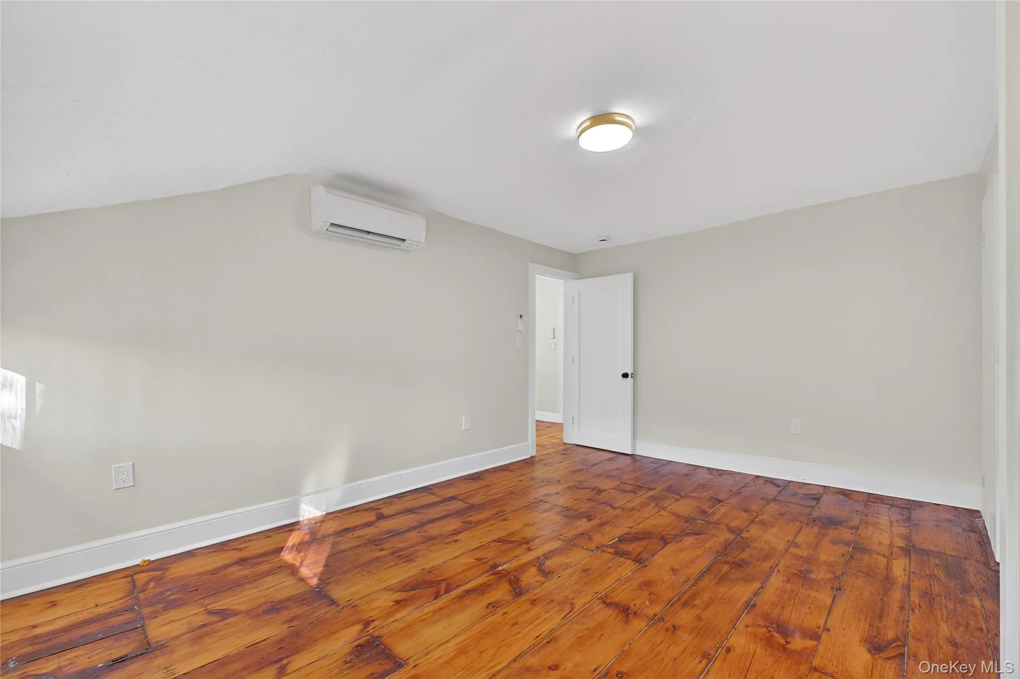 Unfurnished room with wood-type flooring and a wall unit AC Unfurnished room with wood-type flooring and a wall unit AC