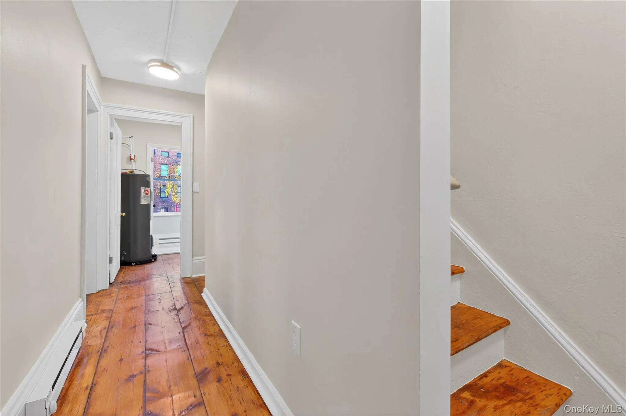 Hallway featuring light wood-style flooring, electric water heater, and a baseboard radiator Hallway featuring light wood-style flooring, electric water heater, and a baseboard radiator