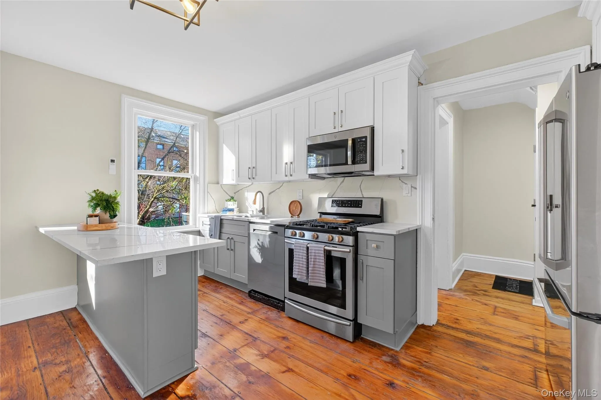 Kitchen with gray cabinets, stainless steel appliances, white cabinetry, and light stone counters Kitchen with gray cabinets, stainless steel appliances, white cabinetry, and light stone counters