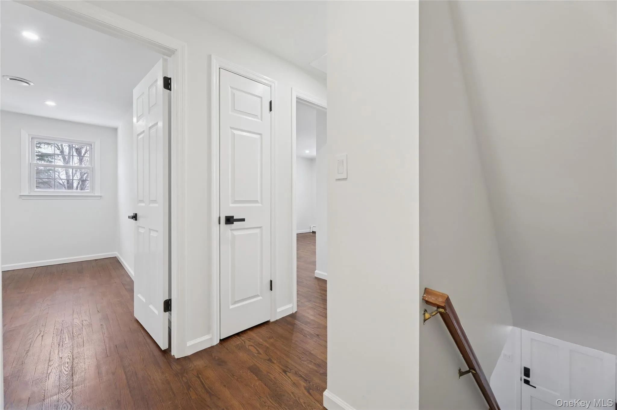 Hallway featuring an upstairs landing, dark wood-style floors, and recessed lighting Hallway featuring an upstairs landing, dark wood-style floors, and recessed lighting
