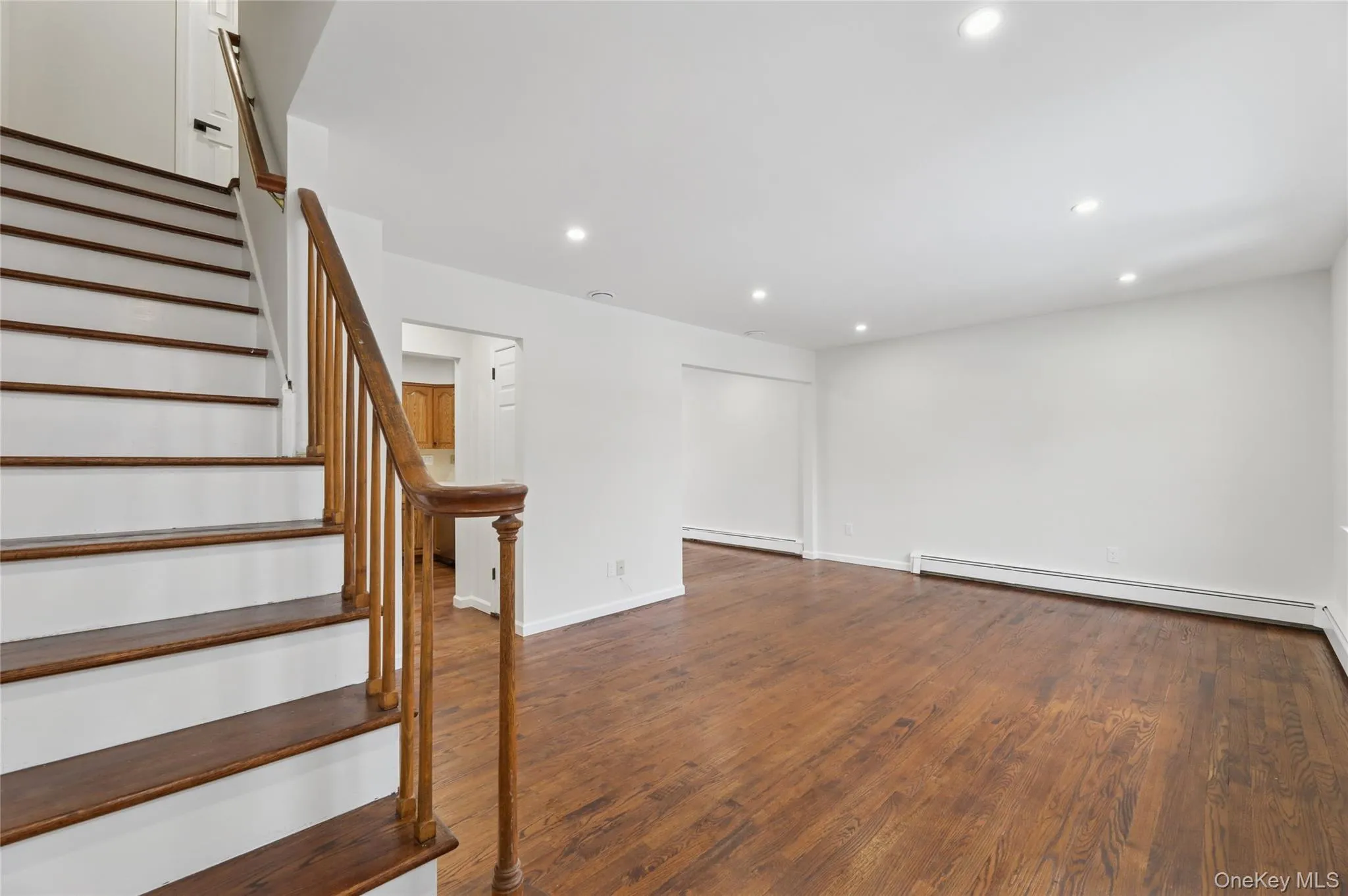 Staircase with wood finished floors, recessed lighting, and a baseboard heating unit Staircase with wood finished floors, recessed lighting, and a baseboard heating unit