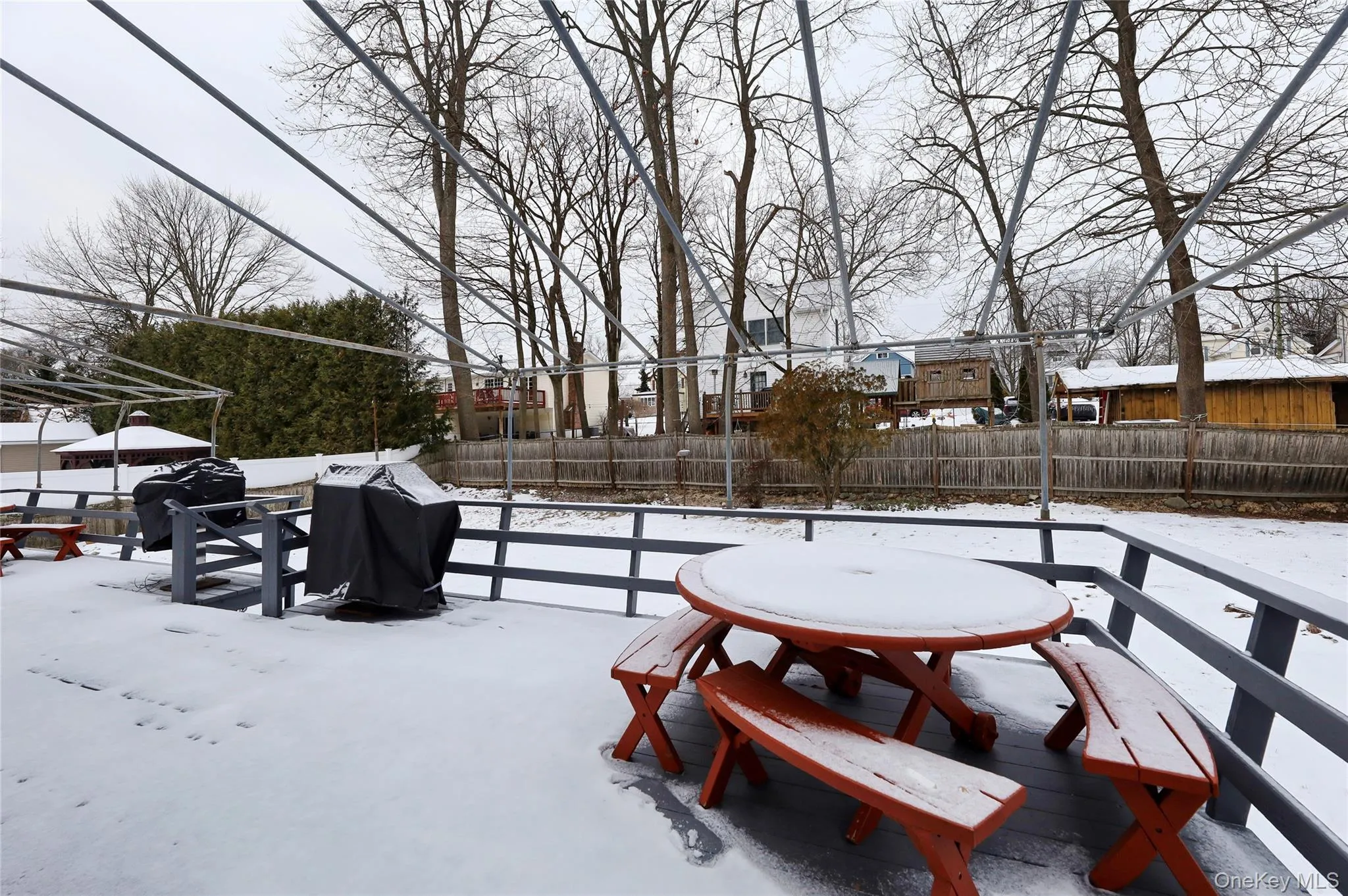 Yard covered in snow with a fenced backyard and a wooden deck Yard covered in snow with a fenced backyard and a wooden deck
