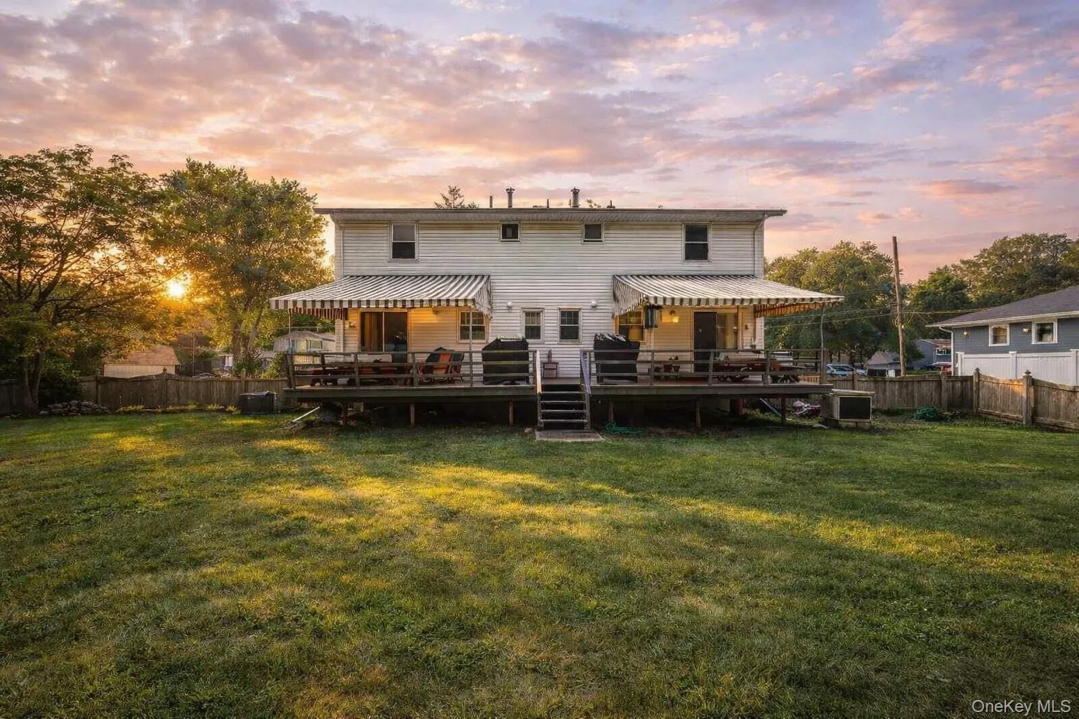 Back of property at dusk featuring a fenced backyard and a wooden deck Back of property at dusk featuring a fenced backyard and a wooden deck