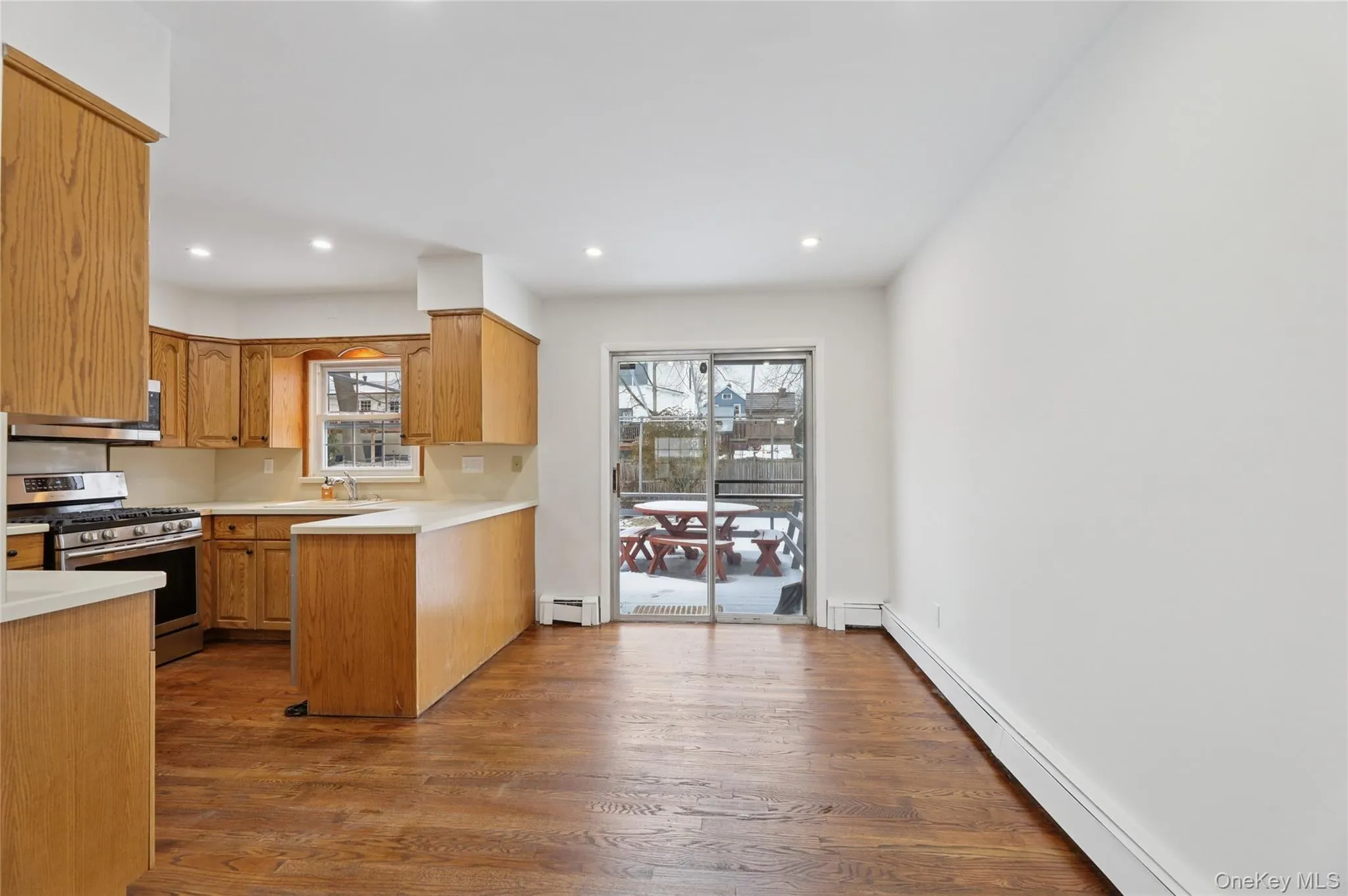 Kitchen with light countertops, baseboard heating, stainless steel appliances, dark wood-type flooring, and recessed lighting Kitchen with light countertops, baseboard heating, stainless steel appliances, dark wood-type flooring, and recessed lighting