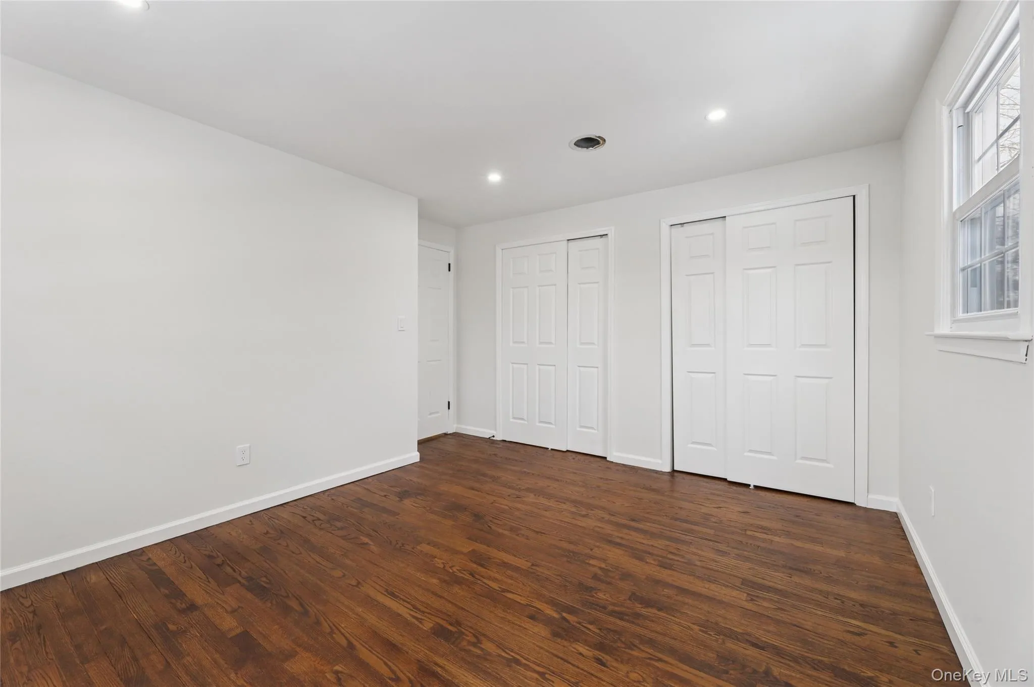 Unfurnished bedroom featuring two closets, dark wood-type flooring, and recessed lighting Unfurnished bedroom featuring two closets, dark wood-type flooring, and recessed lighting