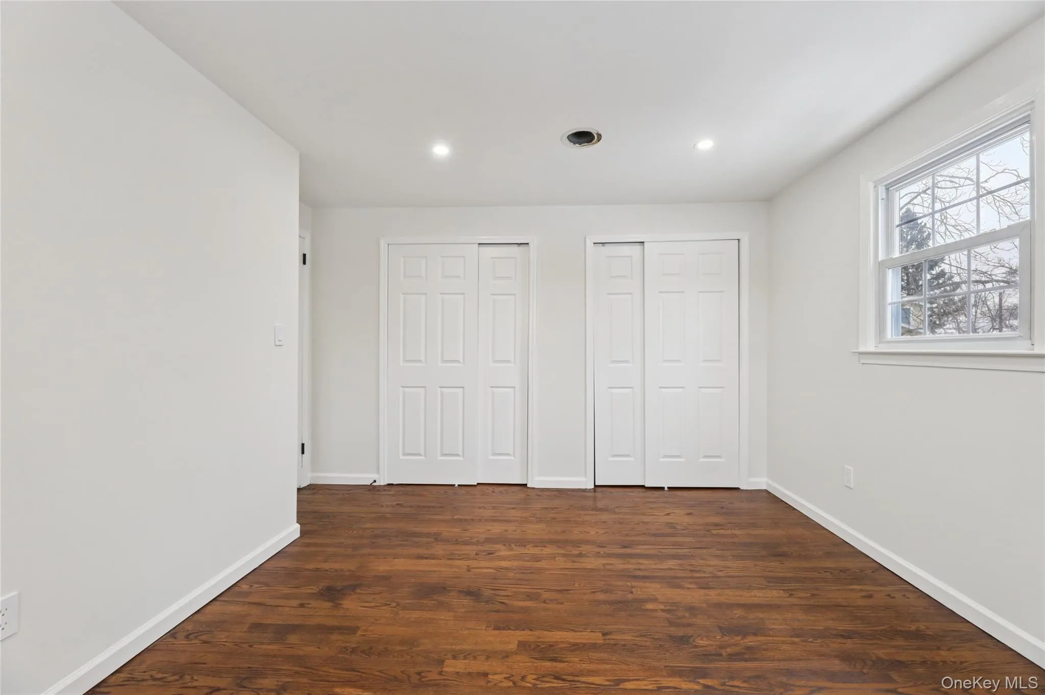 Unfurnished bedroom featuring two closets, dark wood-style flooring, and recessed lighting Unfurnished bedroom featuring two closets, dark wood-style flooring, and recessed lighting