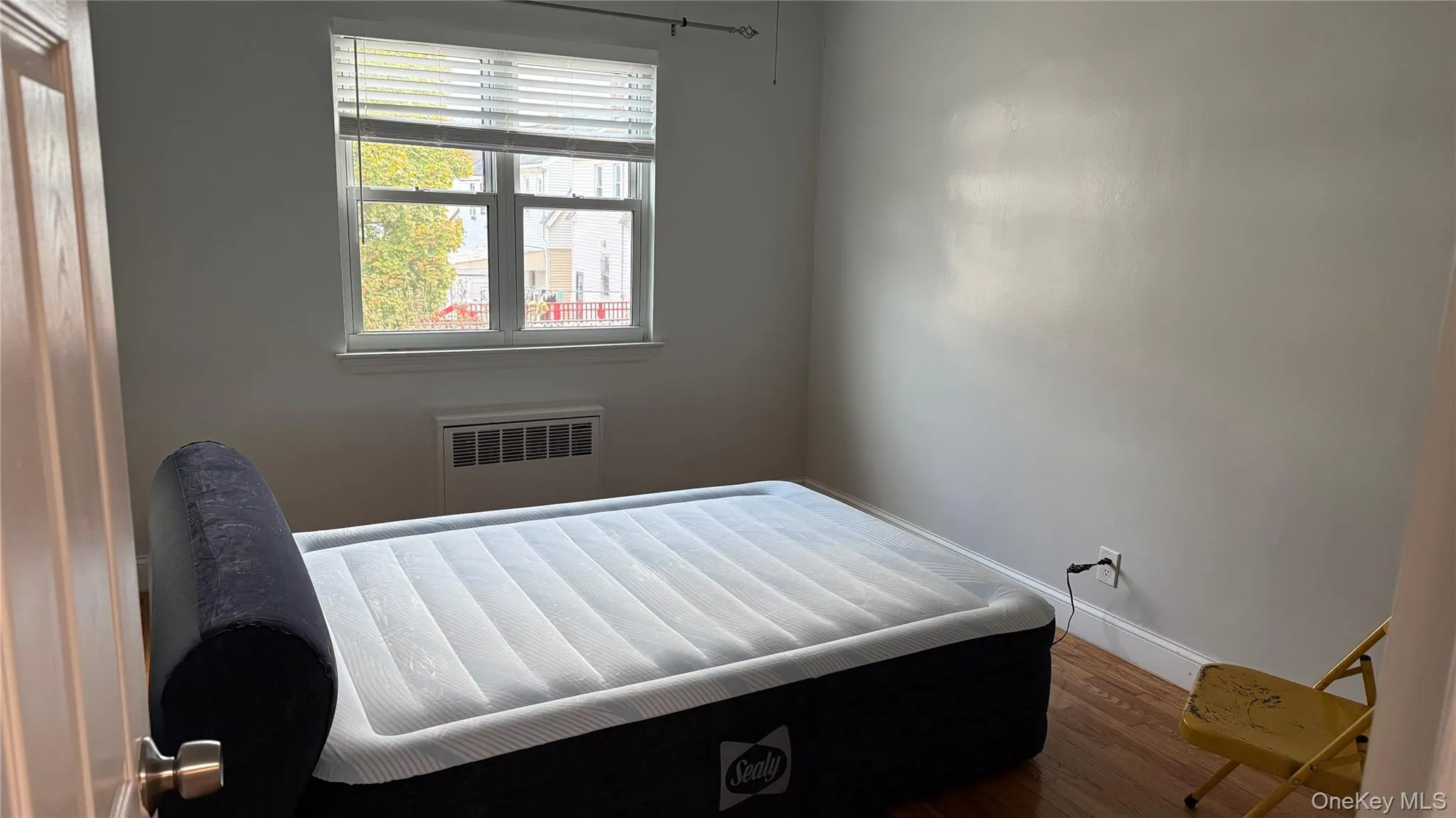 Bedroom with wood finished floors and radiator heating unit Bedroom with wood finished floors and radiator heating unit