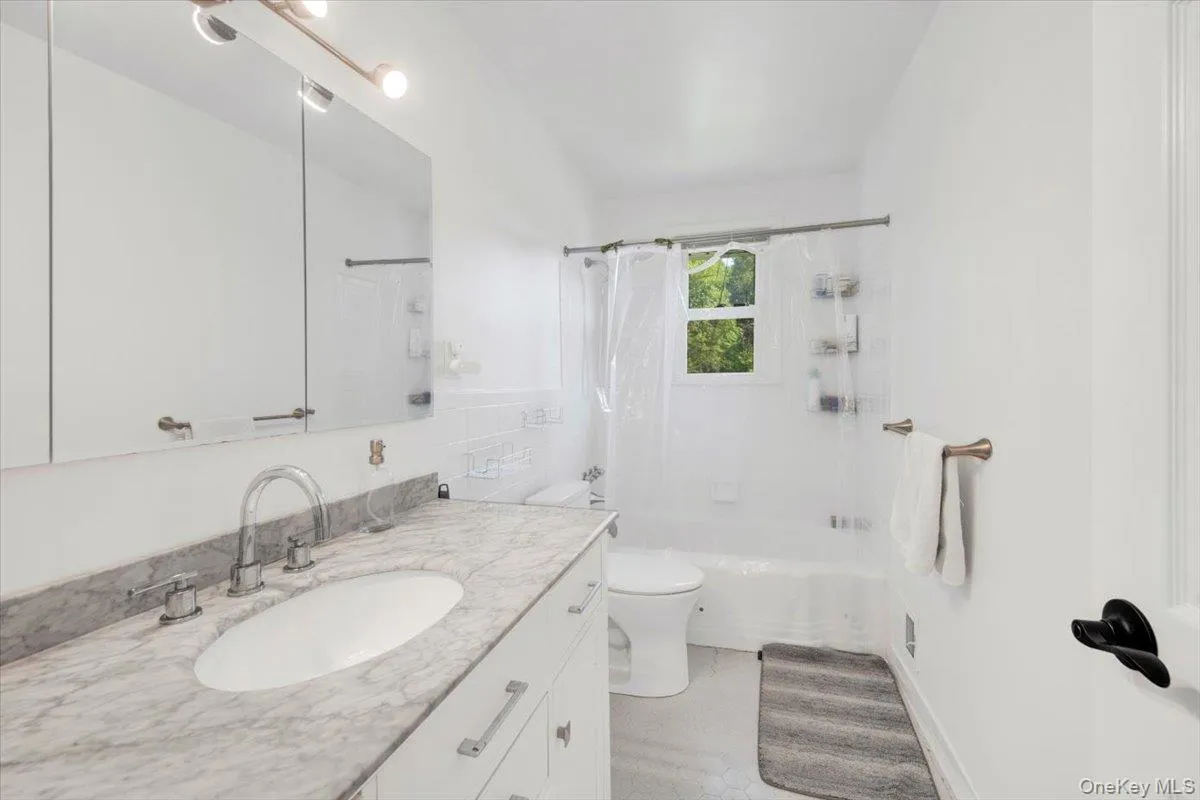 Bathroom featuring vanity, shower / bathtub combination with curtain, and tile walls Bathroom featuring vanity, shower / bathtub combination with curtain, and tile walls