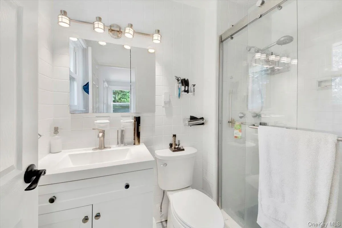 Bathroom with tile walls, a shower stall, vanity, and decorative backsplash Bathroom with tile walls, a shower stall, vanity, and decorative backsplash