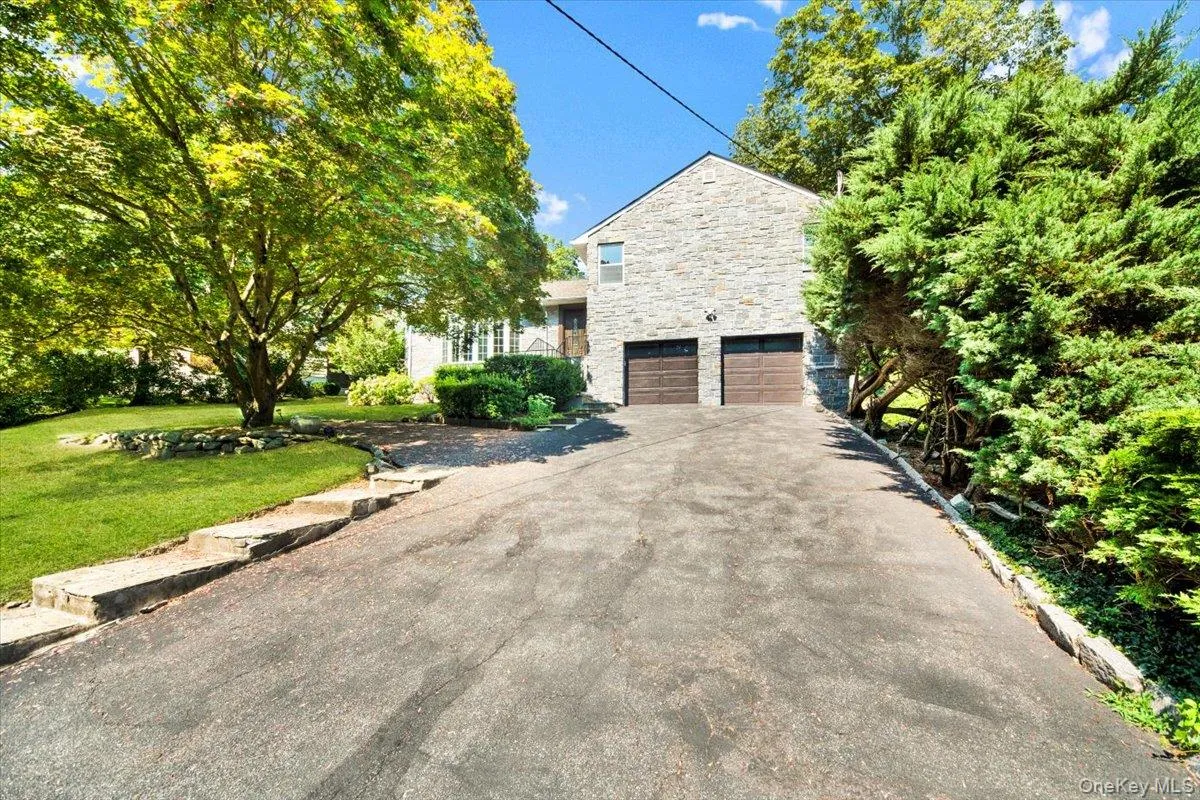 View of front of property with stone siding, an attached garage, asphalt driveway, and a front lawn View of front of property with stone siding, an attached garage, asphalt driveway, and a front lawn