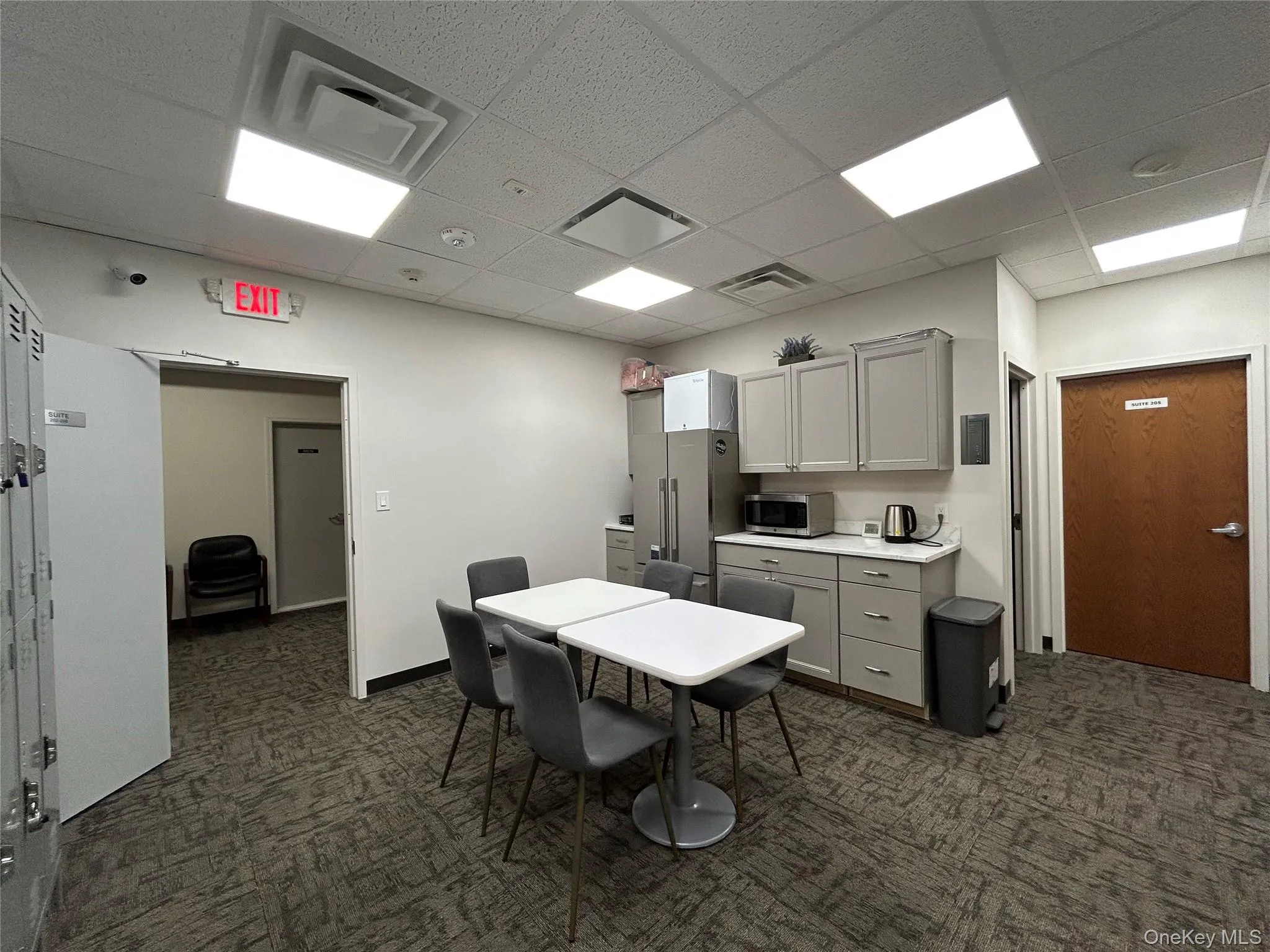Common area-Kitchen featuring gray cabinets, a drop ceiling, light countertops, and stainless steel microwave Common area-Kitchen featuring gray cabinets, a drop ceiling, light countertops, and stainless steel microwave