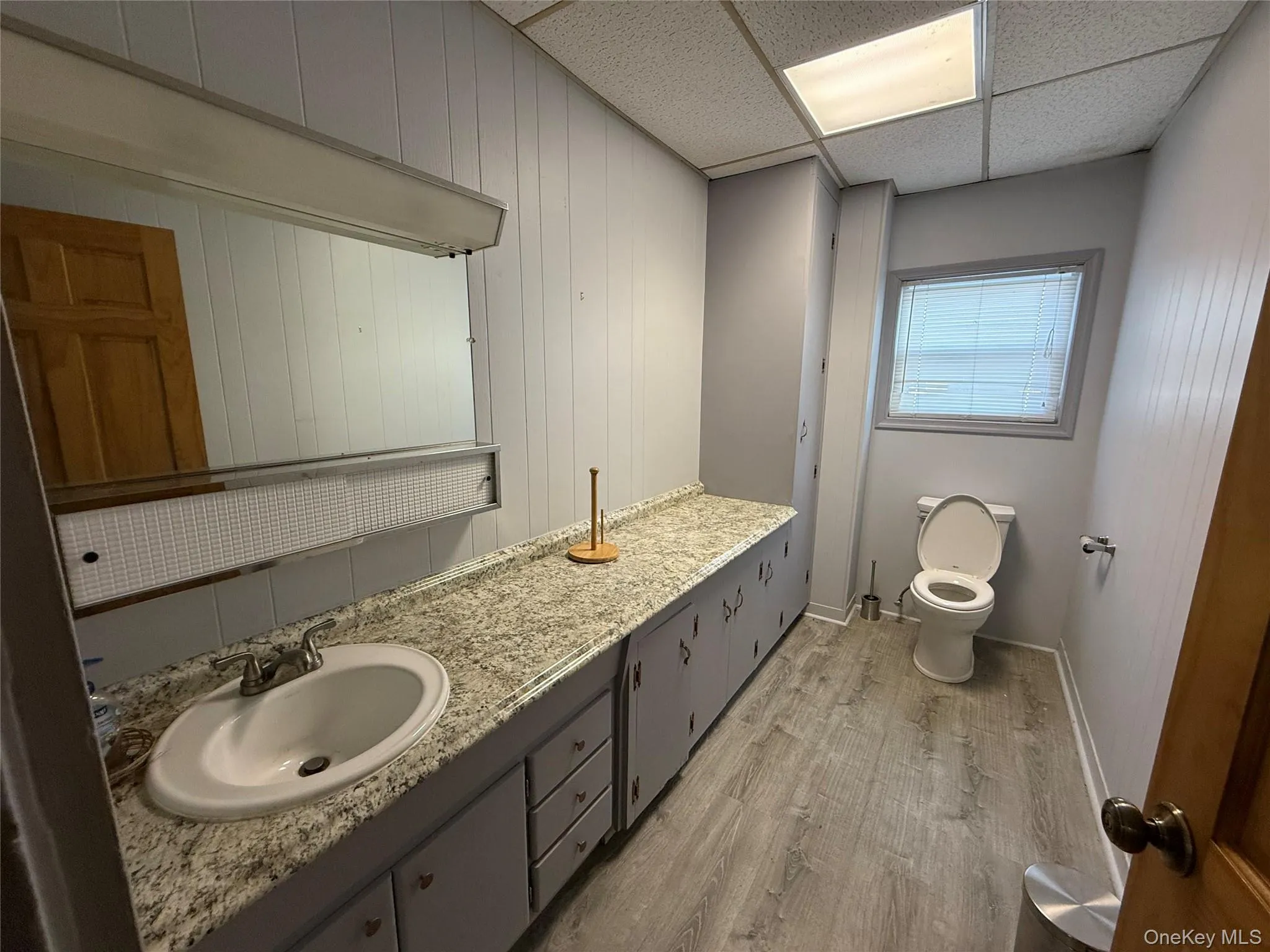 Bathroom with light wood finished floors, vanity, and a paneled ceiling Bathroom with light wood finished floors, vanity, and a paneled ceiling