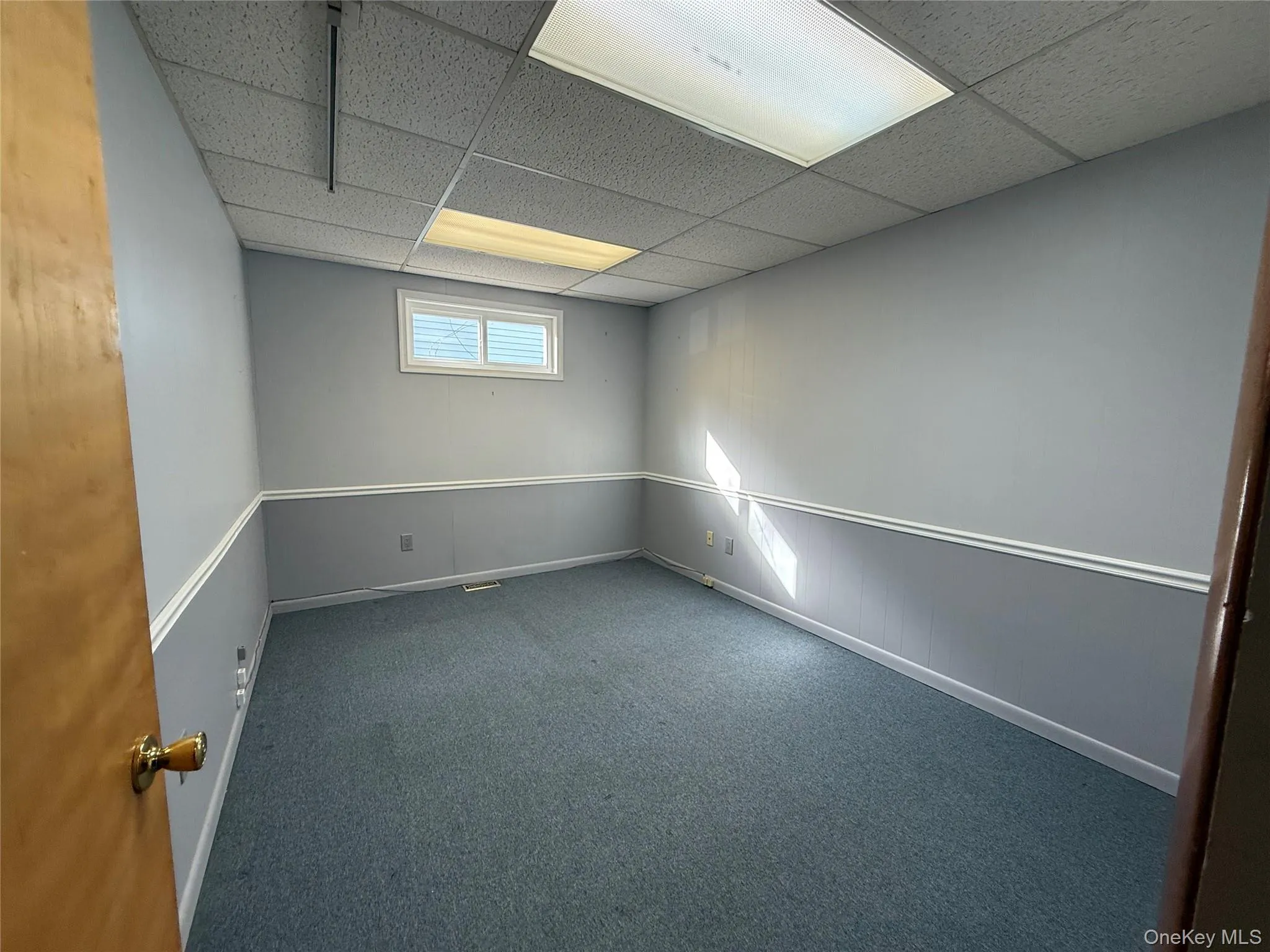 Spare room with a drop ceiling and dark colored carpet Spare room with a drop ceiling and dark colored carpet