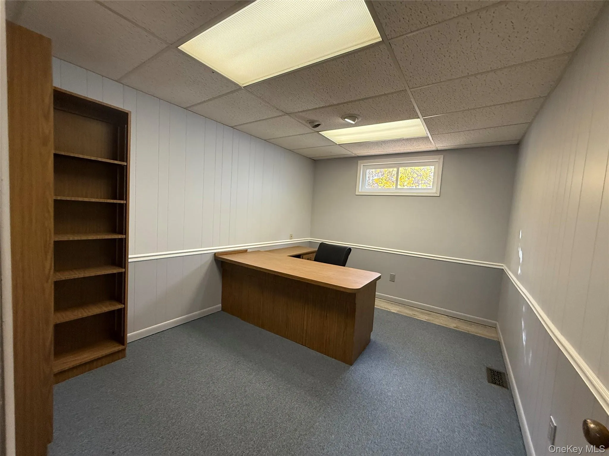Unfurnished office with wood walls, a paneled ceiling, dark carpet, and built in features Unfurnished office with wood walls, a paneled ceiling, dark carpet, and built in features