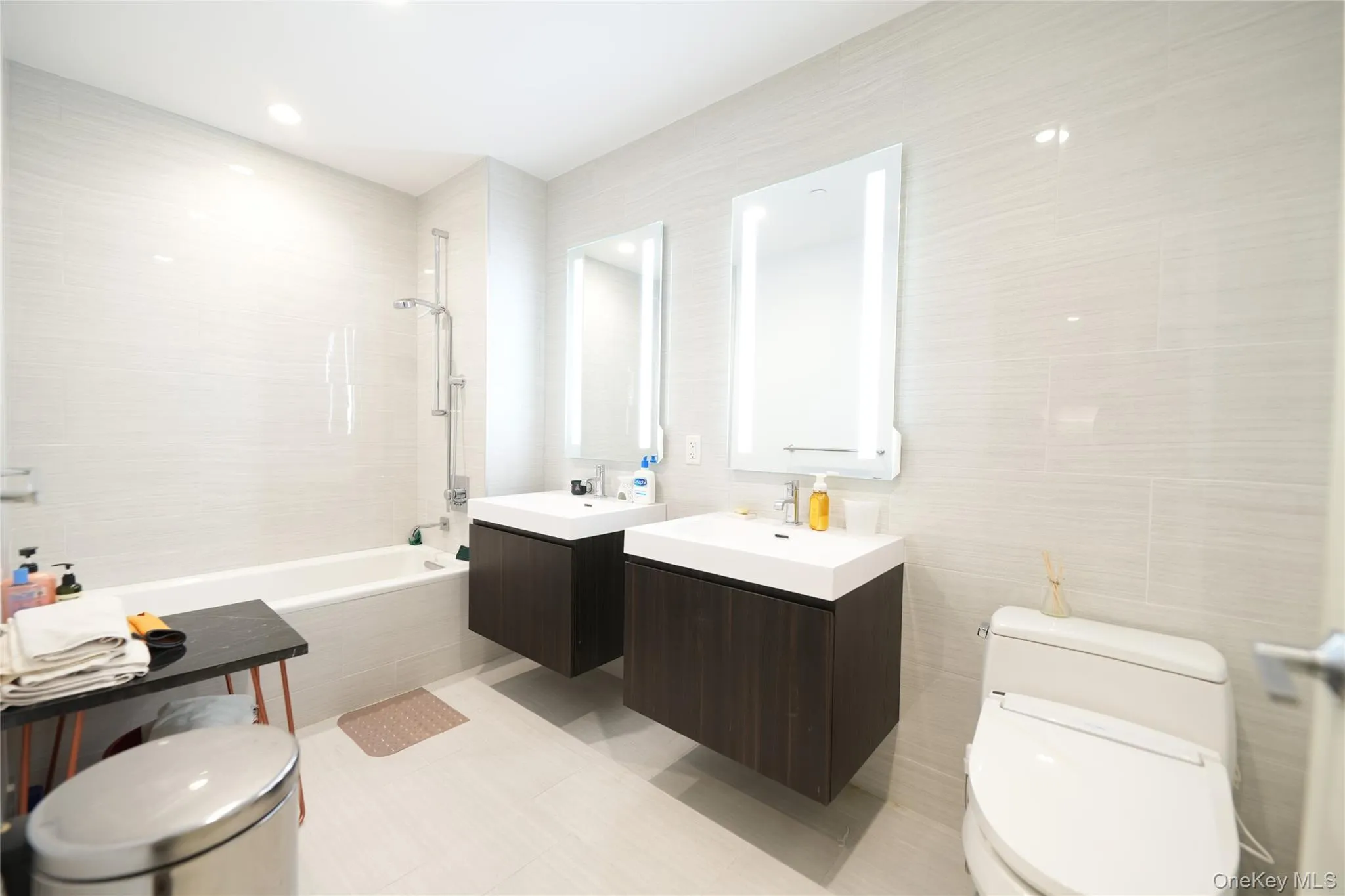 Bathroom with two vanities, tiled shower / bath, tile walls, and recessed lighting Bathroom with two vanities, tiled shower / bath, tile walls, and recessed lighting