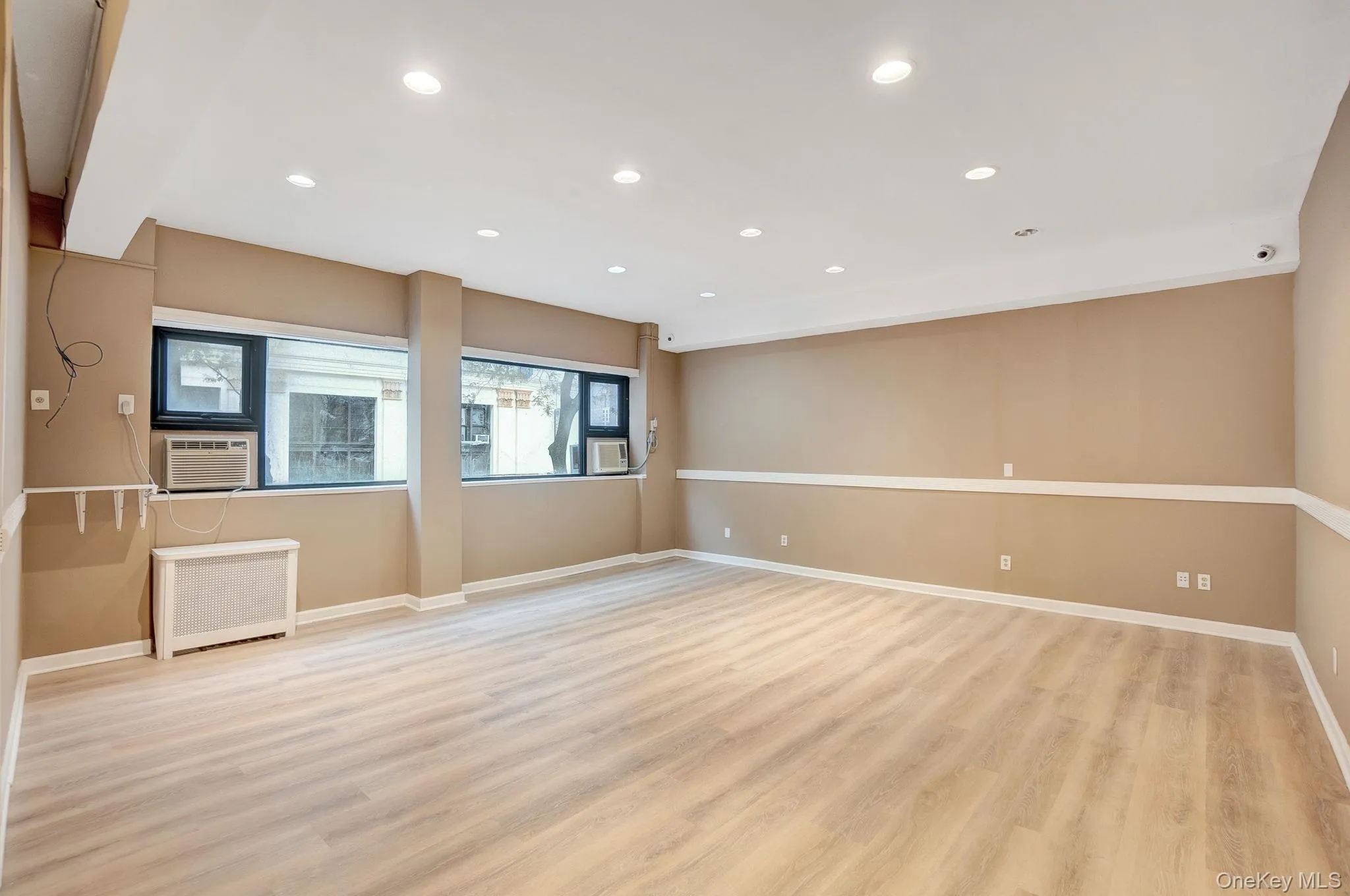 Unfurnished room with light wood-style flooring, recessed lighting, and radiator heating unit Unfurnished room with light wood-style flooring, recessed lighting, and radiator heating unit