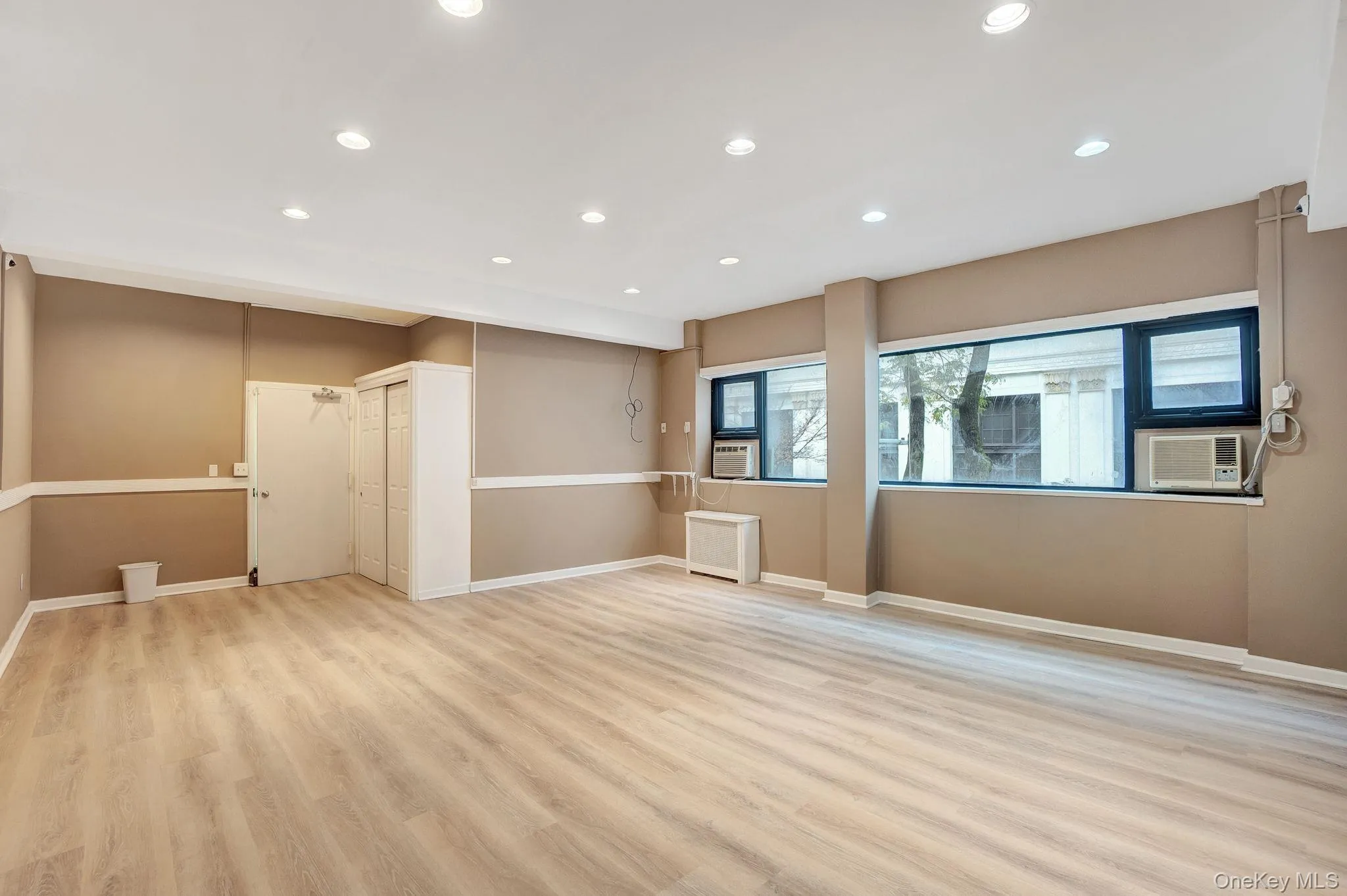 Empty room featuring light wood-style flooring, recessed lighting, and radiator Empty room featuring light wood-style flooring, recessed lighting, and radiator