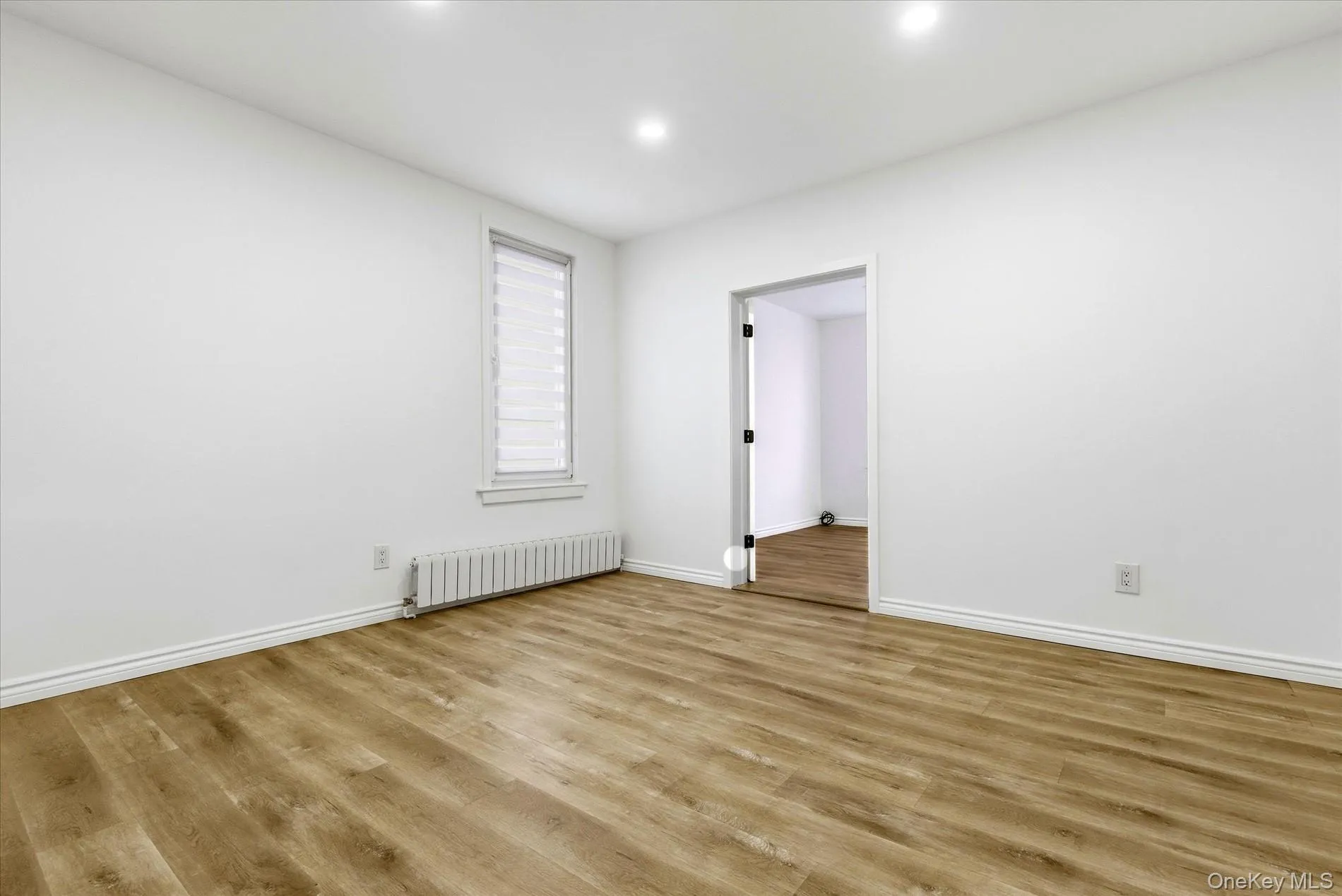 Spare room featuring radiator heating unit, wood finished floors, and recessed lighting Spare room featuring radiator heating unit, wood finished floors, and recessed lighting
