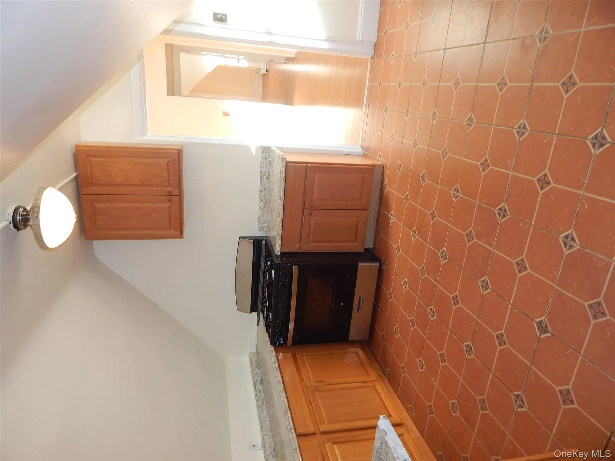 Kitchen with range, brown cabinetry, vaulted ceiling, and light stone countertops Kitchen with range, brown cabinetry, vaulted ceiling, and light stone countertops