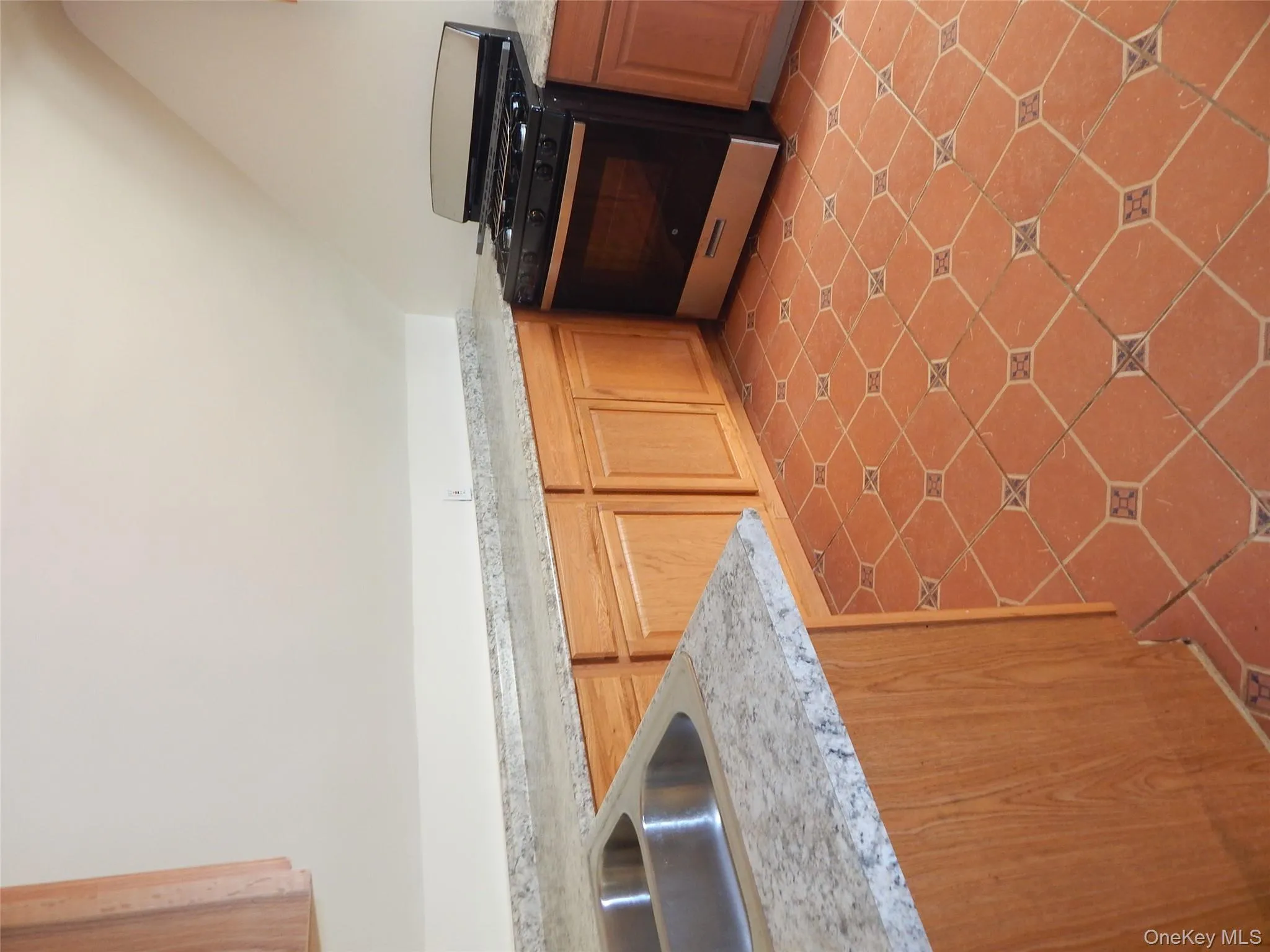 Kitchen with range, vaulted ceiling, light countertops, brown cabinetry, and light tile patterned floors Kitchen with range, vaulted ceiling, light countertops, brown cabinetry, and light tile patterned floors