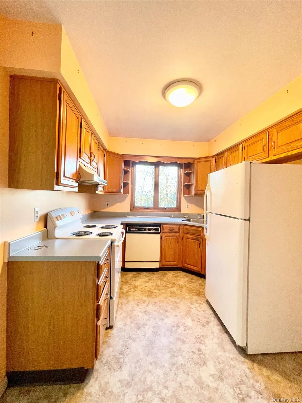 Kitchen with white appliances, open shelves, brown cabinets, and light countertops Kitchen with white appliances, open shelves, brown cabinets, and light countertops
