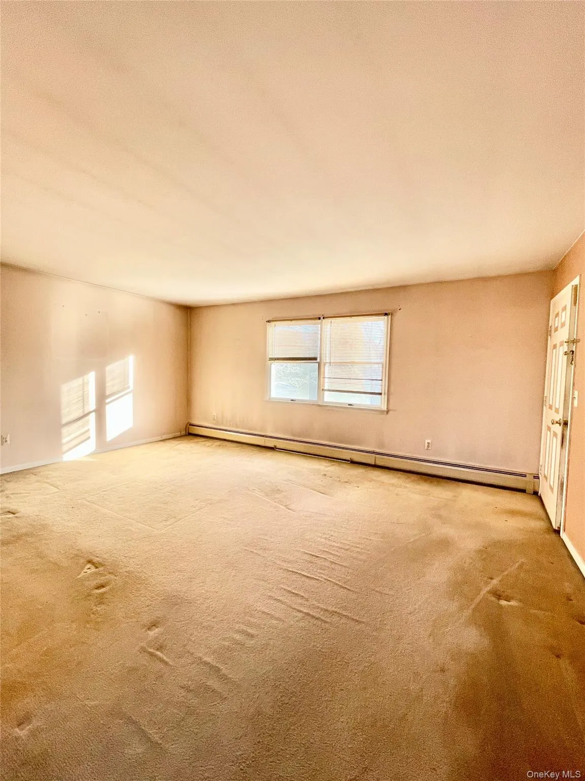 Empty room with carpet and a baseboard radiator Empty room with carpet and a baseboard radiator