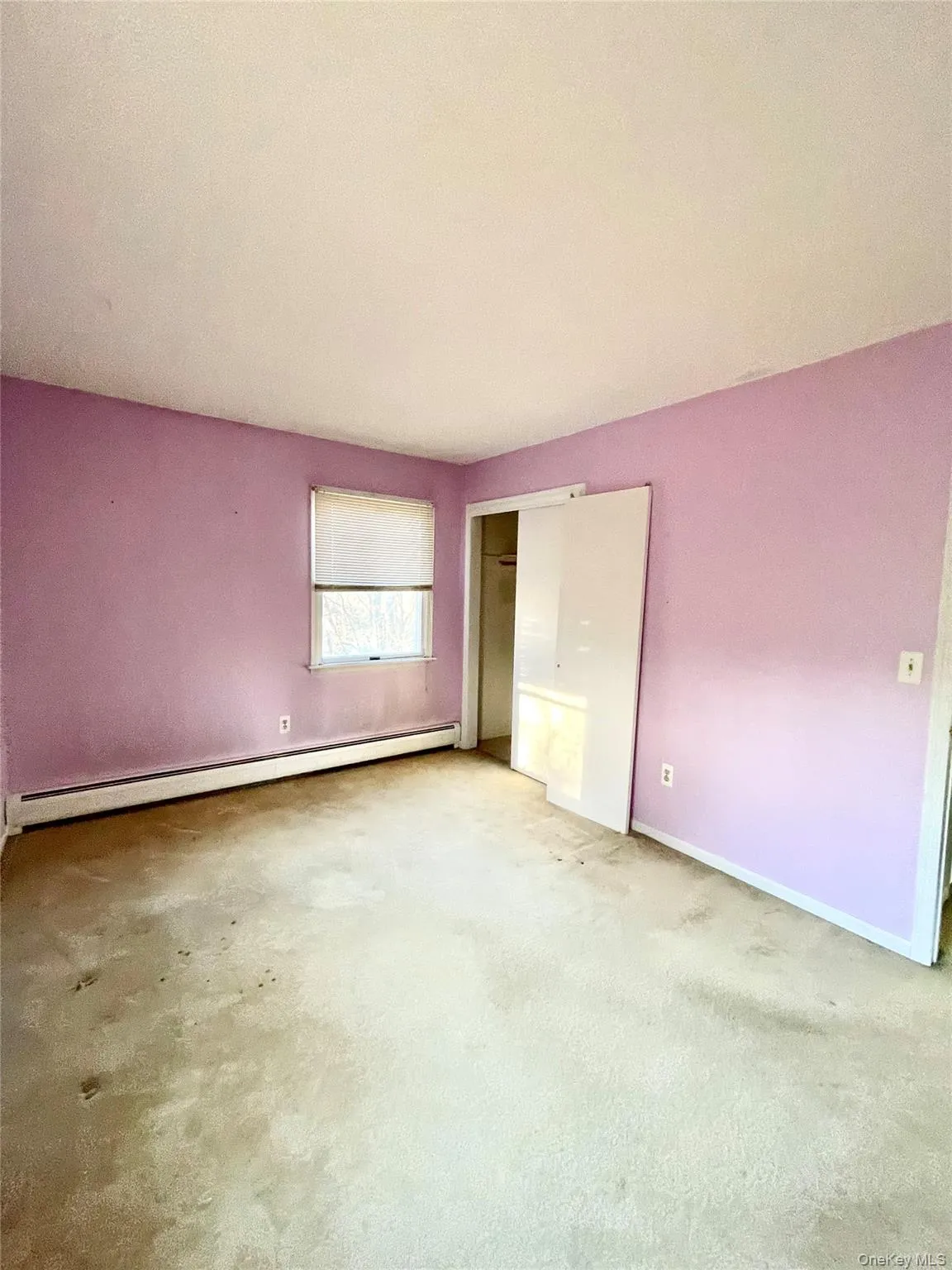 Unfurnished bedroom with baseboard heating and carpet Unfurnished bedroom with baseboard heating and carpet