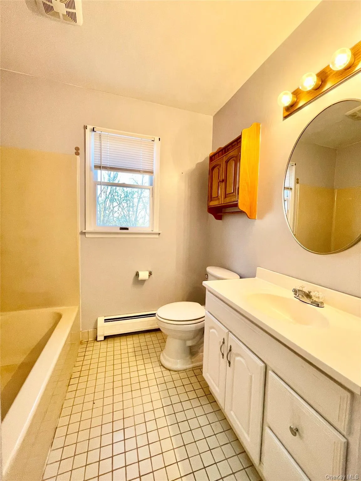 Full bathroom featuring vanity, a baseboard heating unit, and light tile patterned flooring Full bathroom featuring vanity, a baseboard heating unit, and light tile patterned flooring