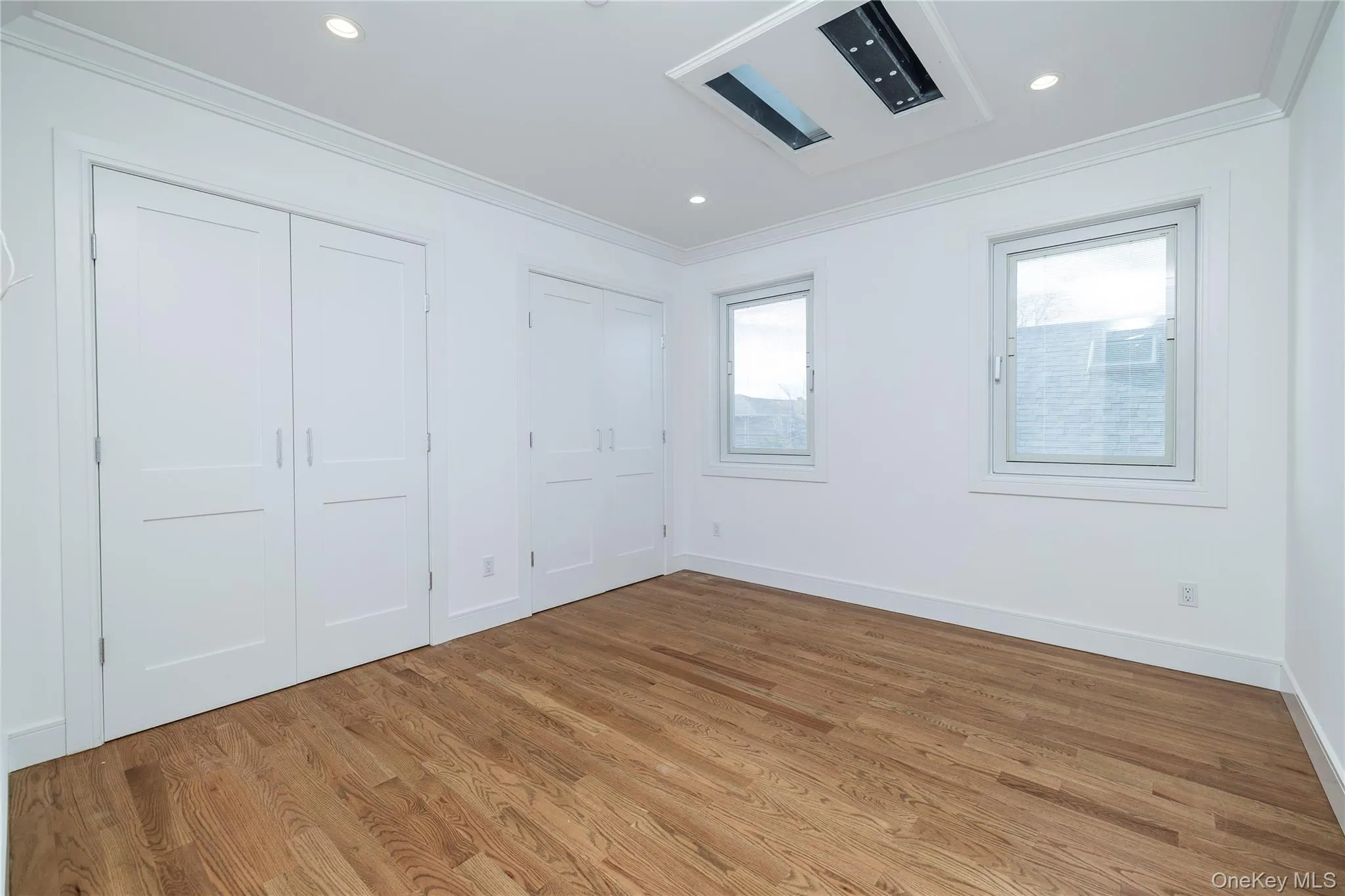 Unfurnished bedroom with wood finished floors, ornamental molding, multiple closets, and recessed lighting Unfurnished bedroom with wood finished floors, ornamental molding, multiple closets, and recessed lighting