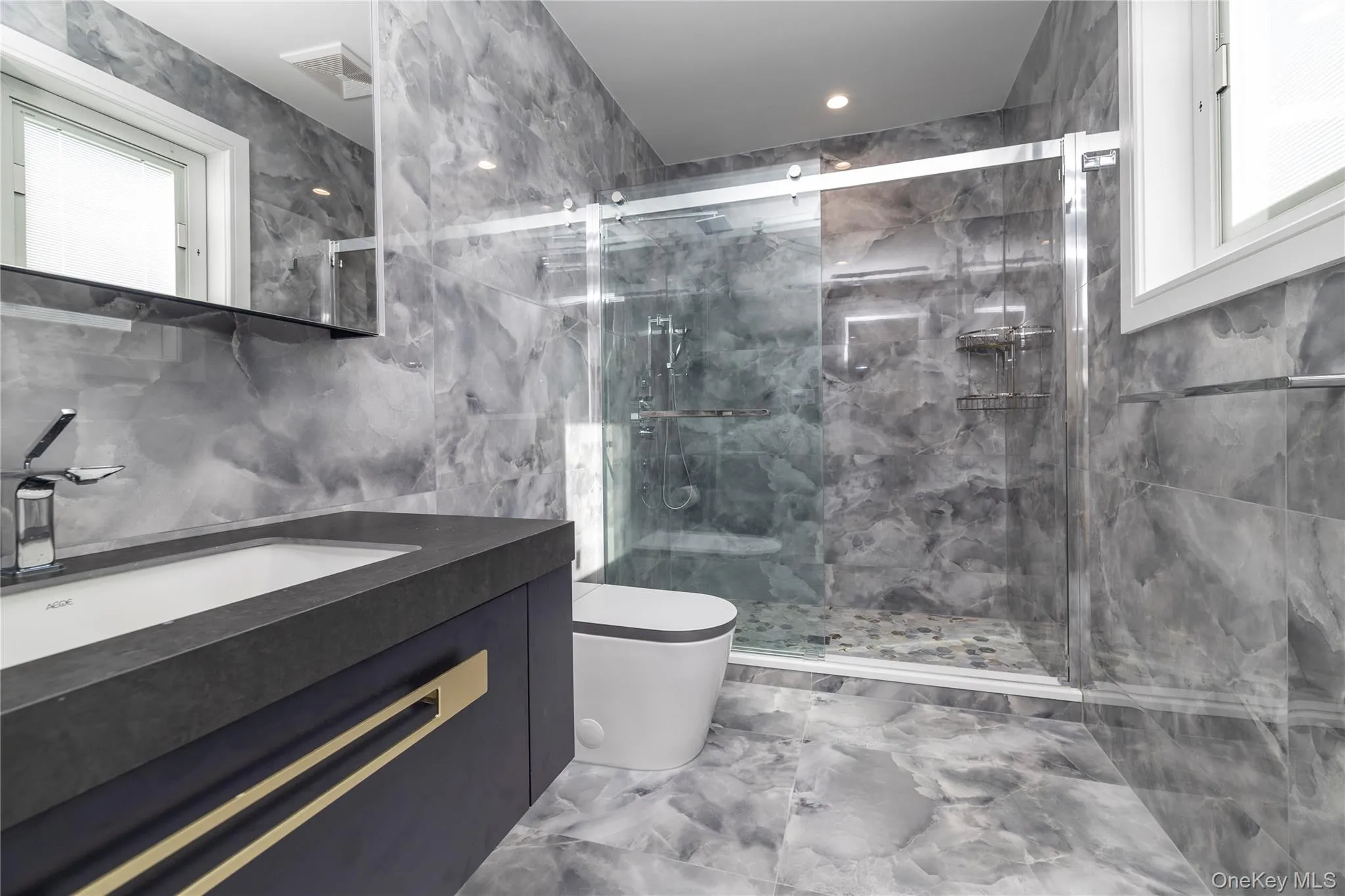 Full bath with tile walls, marble tiled flooring, vanity, and a marble finish shower Full bath with tile walls, marble tiled flooring, vanity, and a marble finish shower