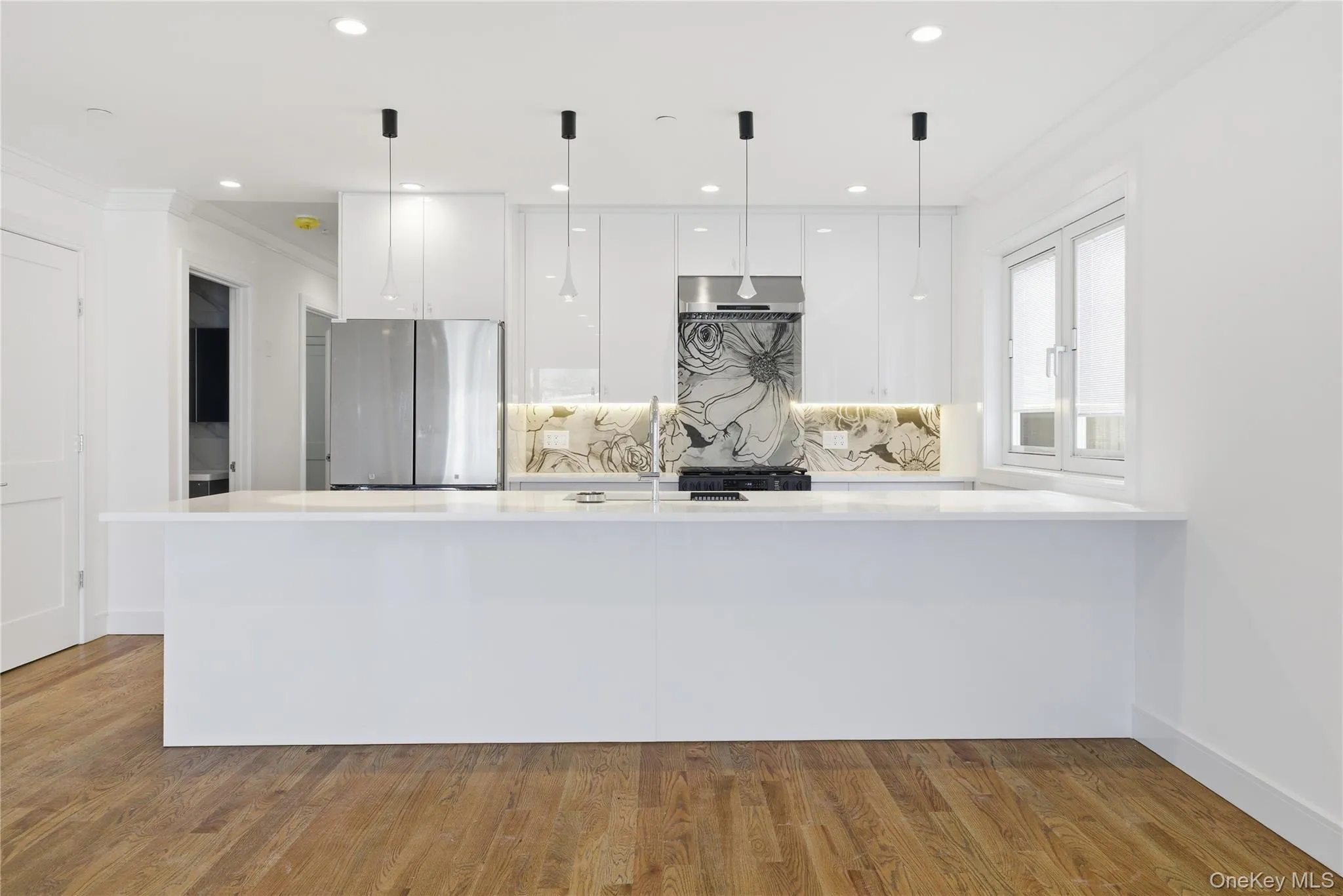 Kitchen featuring white cabinets, modern cabinets, freestanding refrigerator, light wood-style flooring, and light stone counters Kitchen featuring white cabinets, modern cabinets, freestanding refrigerator, light wood-style flooring, and light stone counters