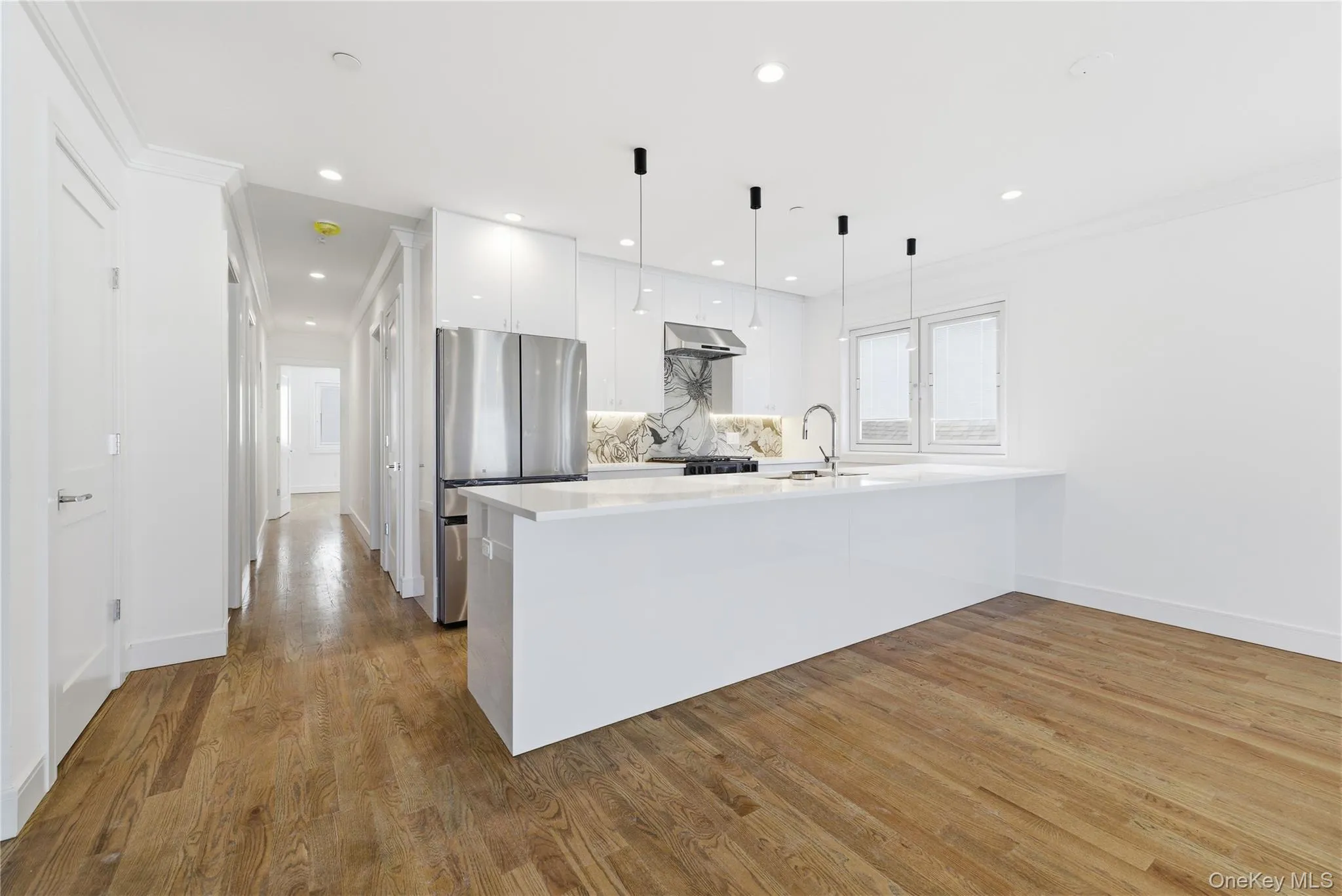 Kitchen with modern cabinets, white cabinets, hanging light fixtures, freestanding refrigerator, and a peninsula Kitchen with modern cabinets, white cabinets, hanging light fixtures, freestanding refrigerator, and a peninsula