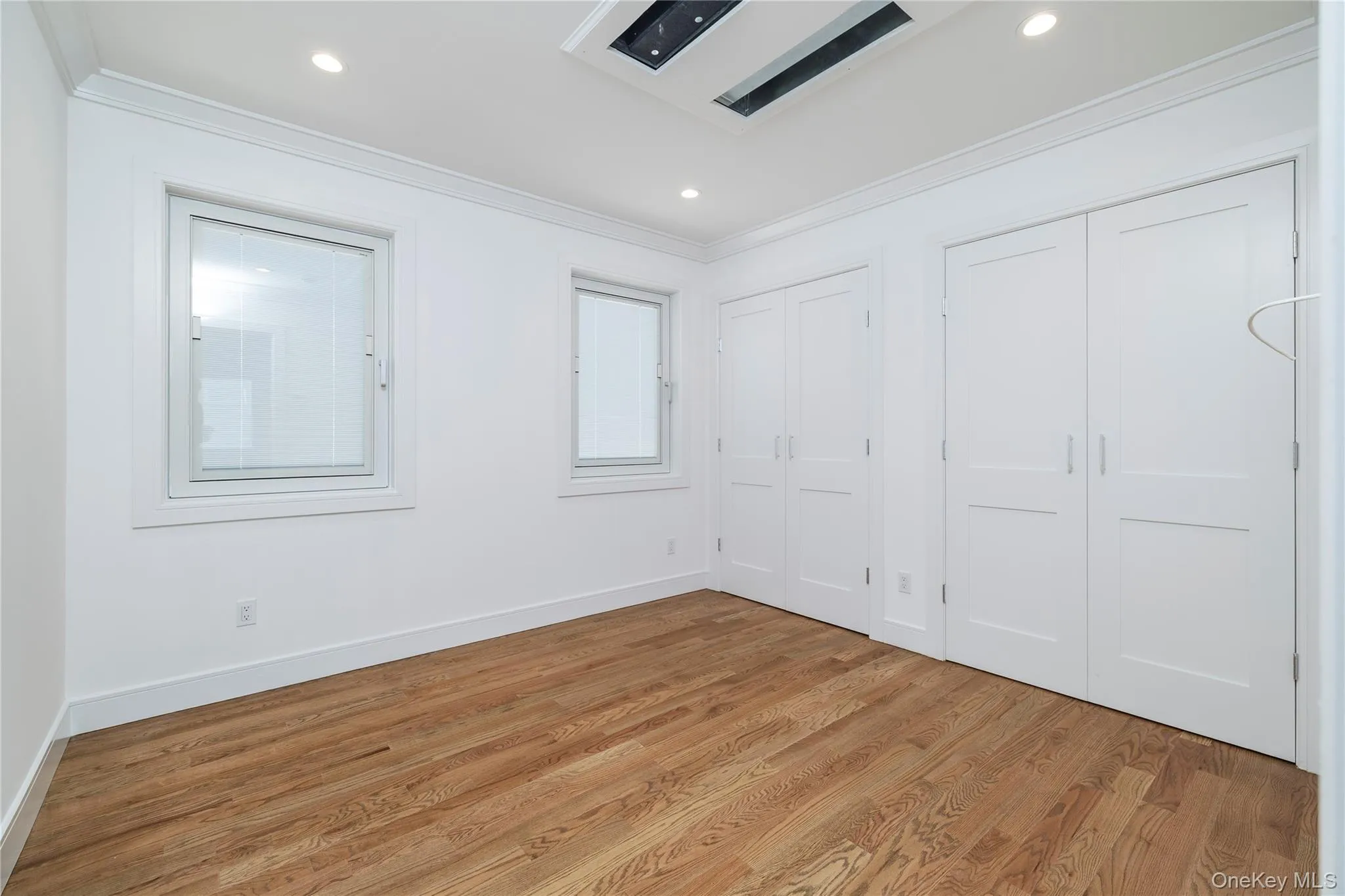 Unfurnished bedroom with multiple closets, wood finished floors, ornamental molding, and recessed lighting Unfurnished bedroom with multiple closets, wood finished floors, ornamental molding, and recessed lighting