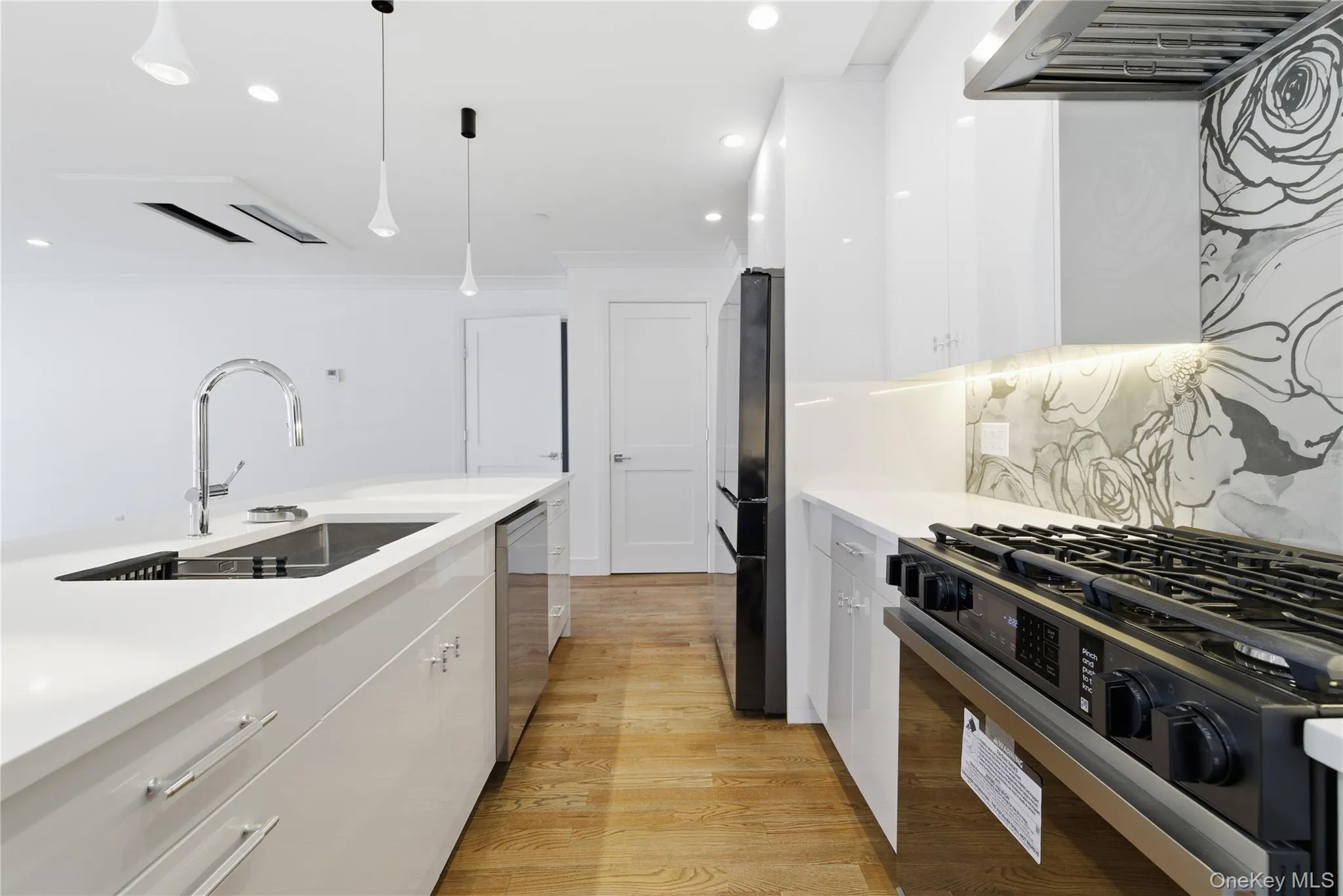 Kitchen featuring white cabinetry, gas range oven, modern cabinets, light wood-style floors, and hanging light fixtures Kitchen featuring white cabinetry, gas range oven, modern cabinets, light wood-style floors, and hanging light fixtures