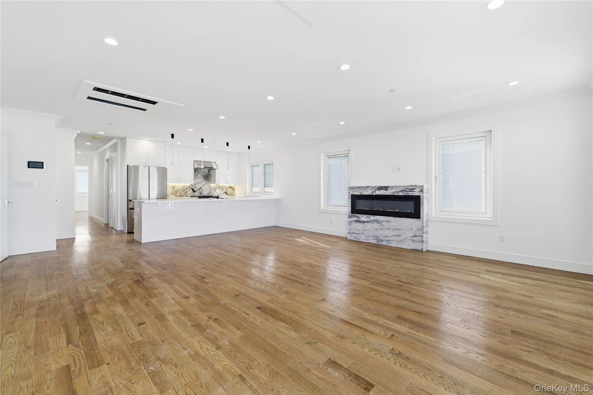 Unfurnished living room with recessed lighting, a fireplace, ornamental molding, and light wood-style floors Unfurnished living room with recessed lighting, a fireplace, ornamental molding, and light wood-style floors