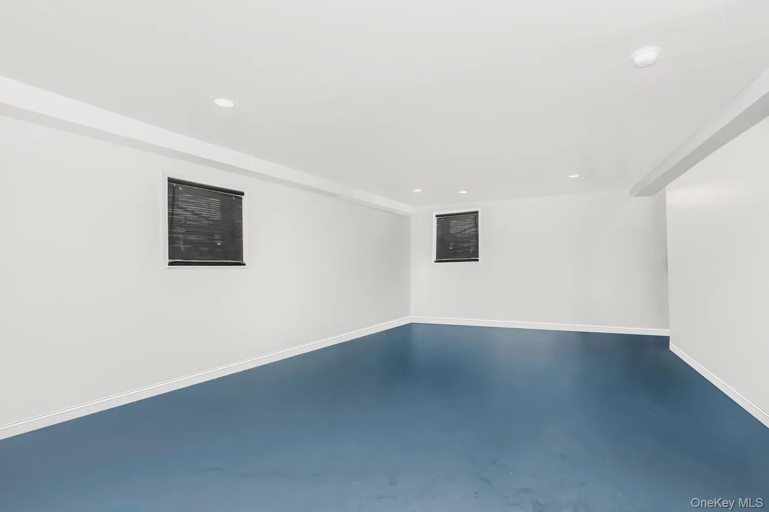 Empty room featuring recessed lighting, finished concrete floors, baseboards, and a smoke detector Empty room featuring recessed lighting, finished concrete floors, baseboards, and a smoke detector