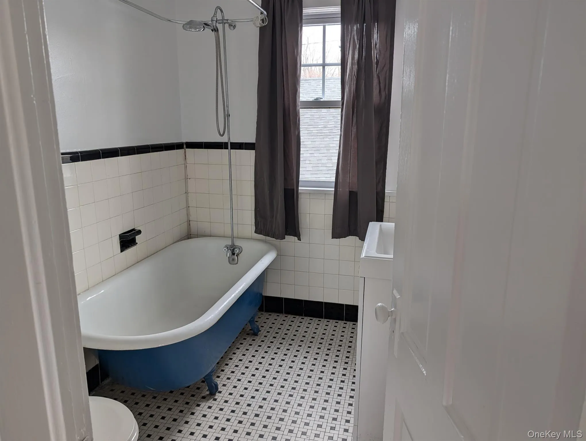 Bathroom with vanity, tile walls, wainscoting, and a combined bath / shower with freestanding tub Bathroom with vanity, tile walls, wainscoting, and a combined bath / shower with freestanding tub