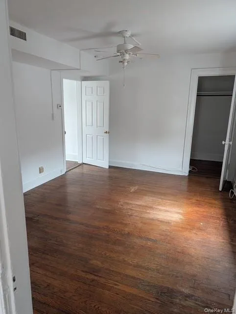 Unfurnished bedroom with dark wood-style floors and a ceiling fan Unfurnished bedroom with dark wood-style floors and a ceiling fan