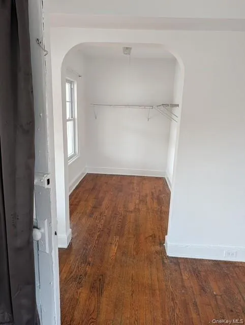 Walk in closet with dark wood-style flooring and arched walkways Walk in closet with dark wood-style flooring and arched walkways