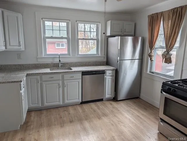 Kitchen with stainless steel appliances, light wood-style flooring, light stone countertops, and healthy amount of natural light Kitchen with stainless steel appliances, light wood-style flooring, light stone countertops, and healthy amount of natural light